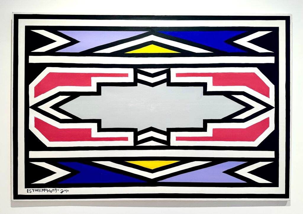 A bold geometric composition featuring a central grey shape surrounded by red, blue, and yellow angular forms.