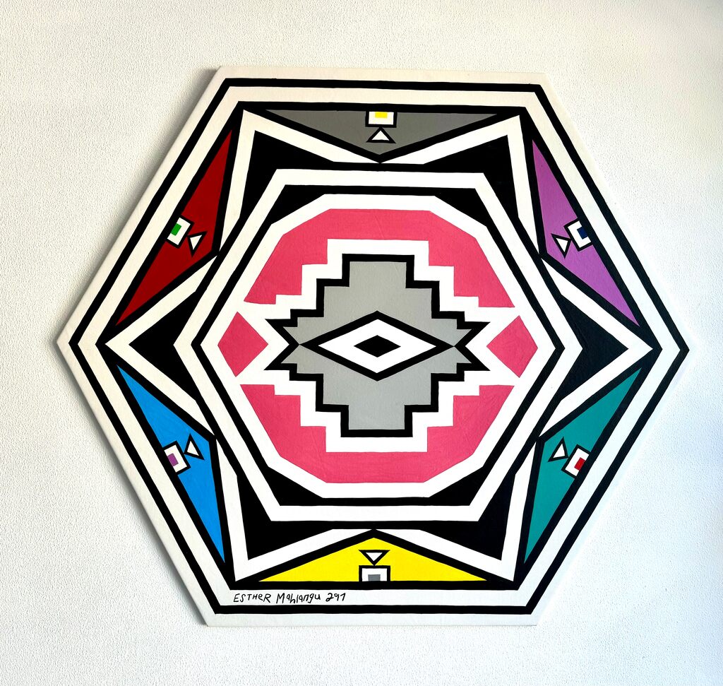 A vibrant geometric mandala featuring a central diamond motif surrounded by concentric hexagonal layers in bold primary and secondary colors.