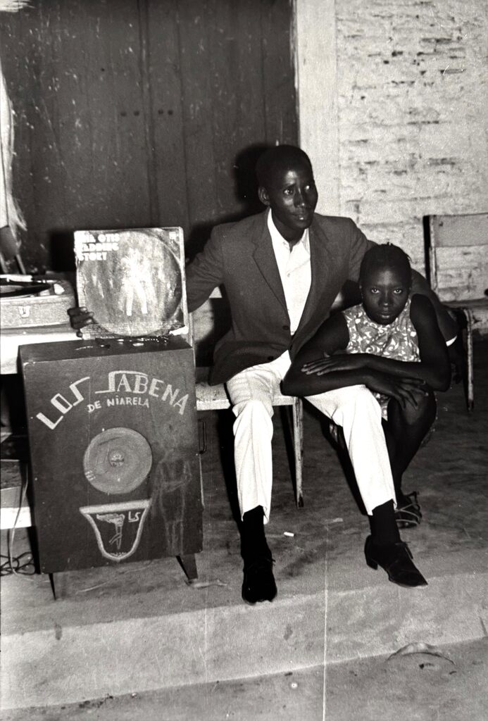A black-and-white portrait of a seated man and child beside a vintage radio.