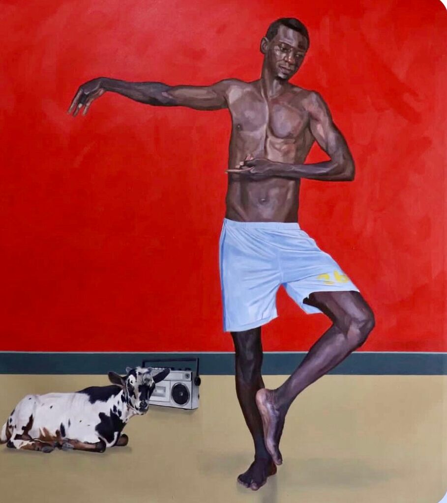 A muscular figure in light shorts dances barefoot against a bold red wall, with a cow and boombox resting on the floor below.