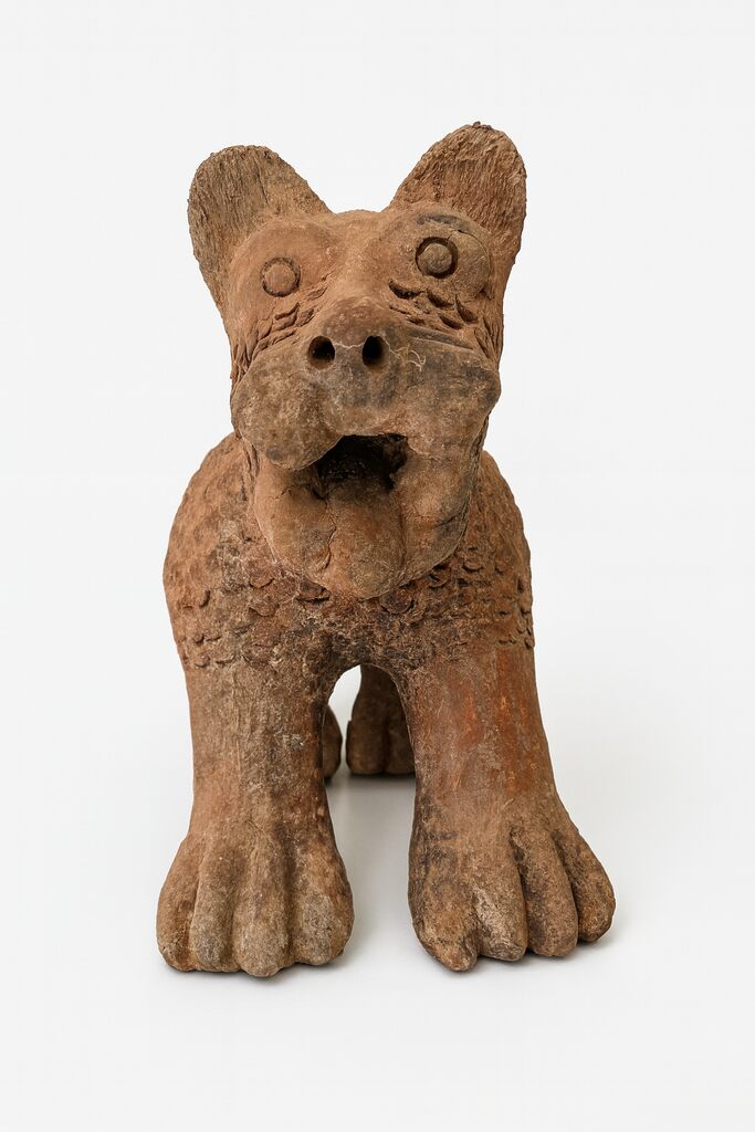 A terracotta sculpture of a four-legged creature with large ears and an open mouth, set against a plain white background.
