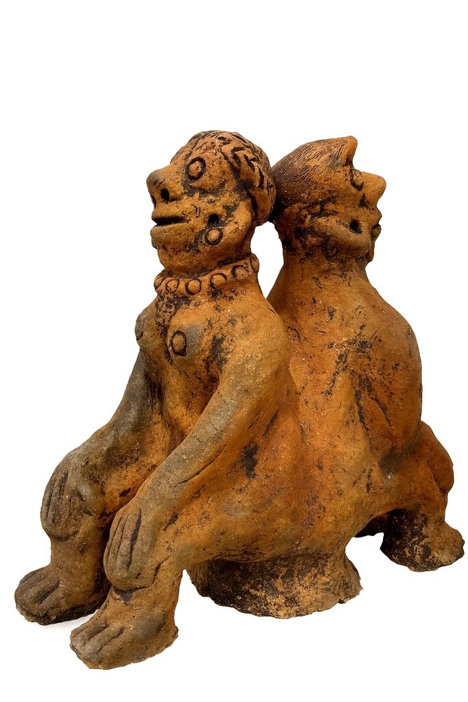 A rustic terracotta sculpture of two seated figures embracing.