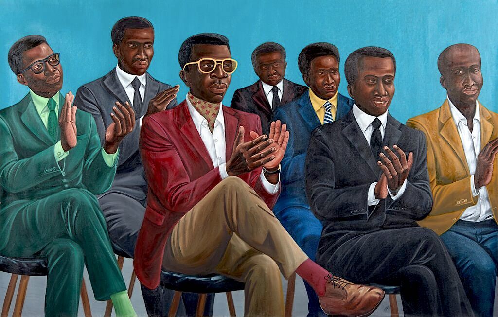A group portrait of seven men in suits clapping against a solid blue background.