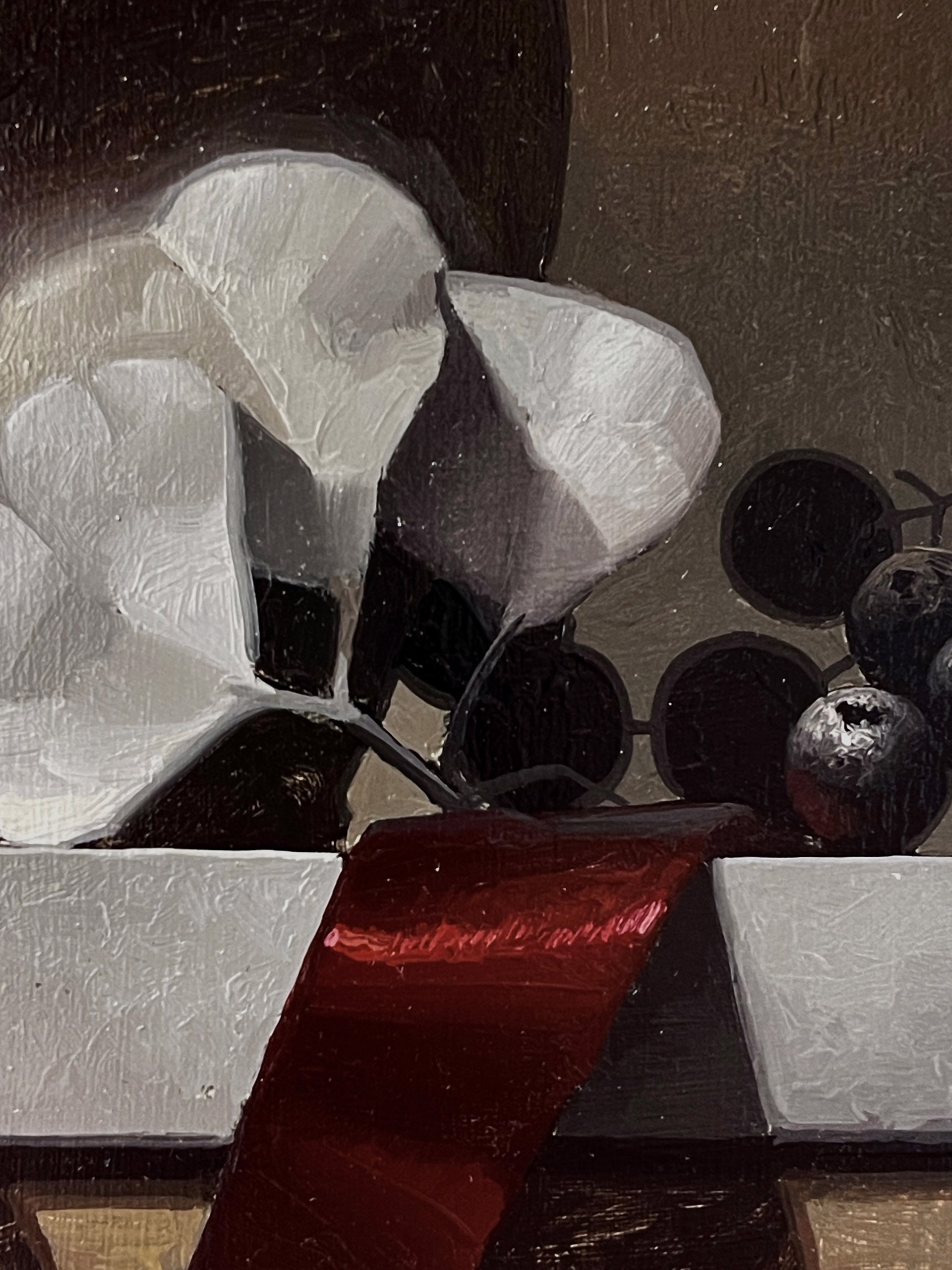 A dark still life featuring a ceramic jug, white flowers, and grapes on a ribbon-draped ledge.