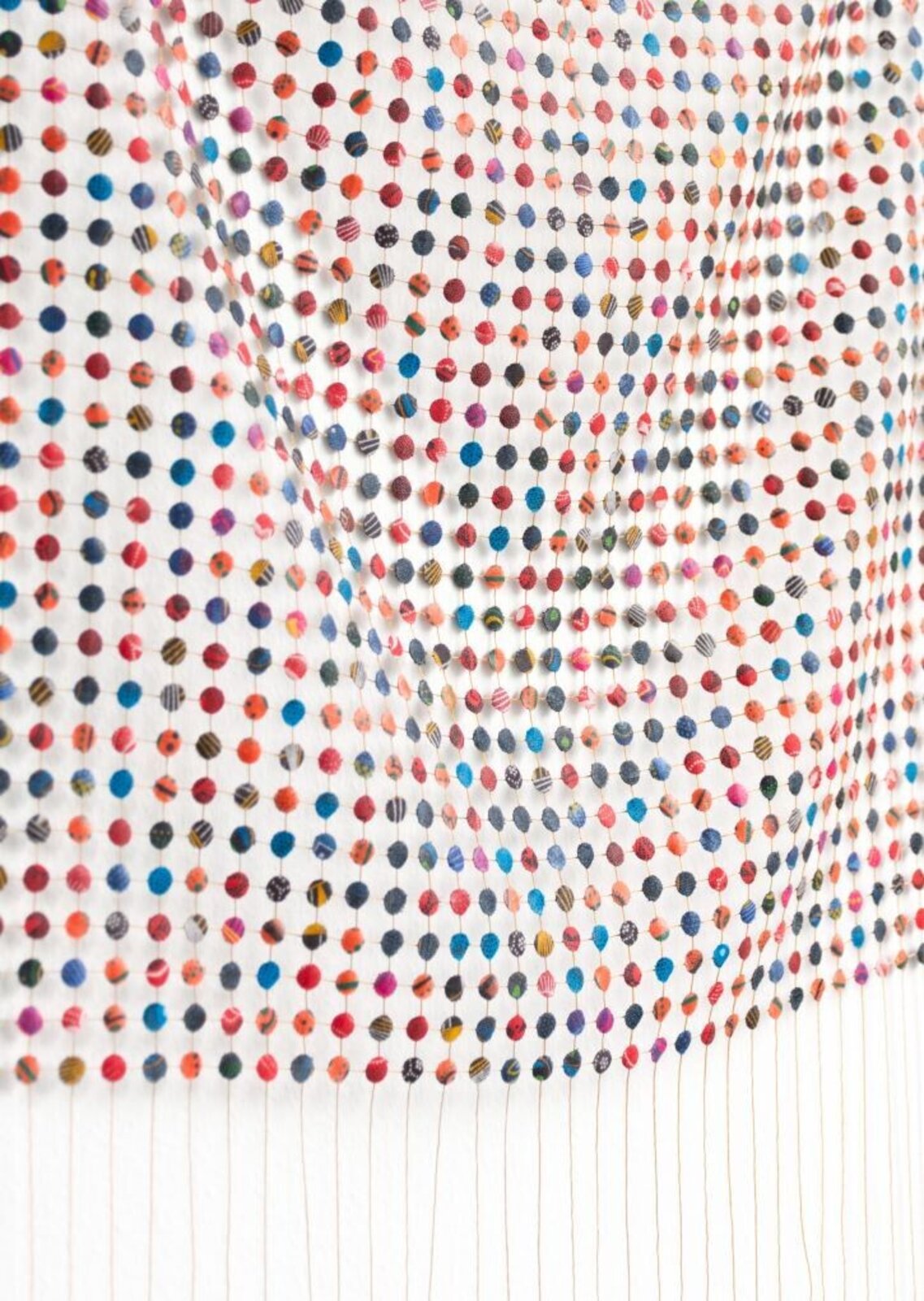 A colorful grid of small, patterned spheres arranged in a wavy formation against a stark white background.