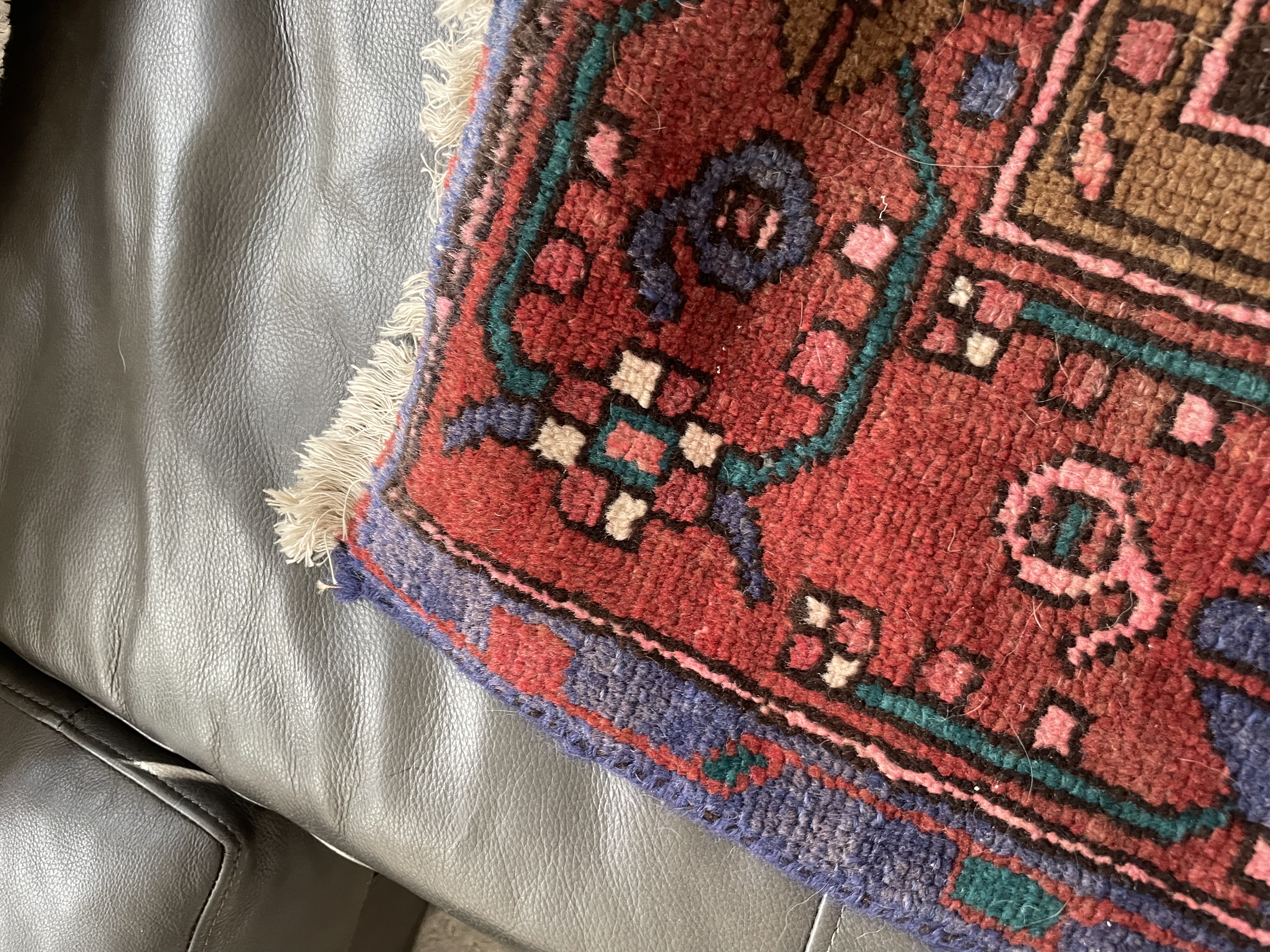 A traditional runner rug with a central medallion design, featuring geometric patterns and a rich palette of reds, purples, and blues.