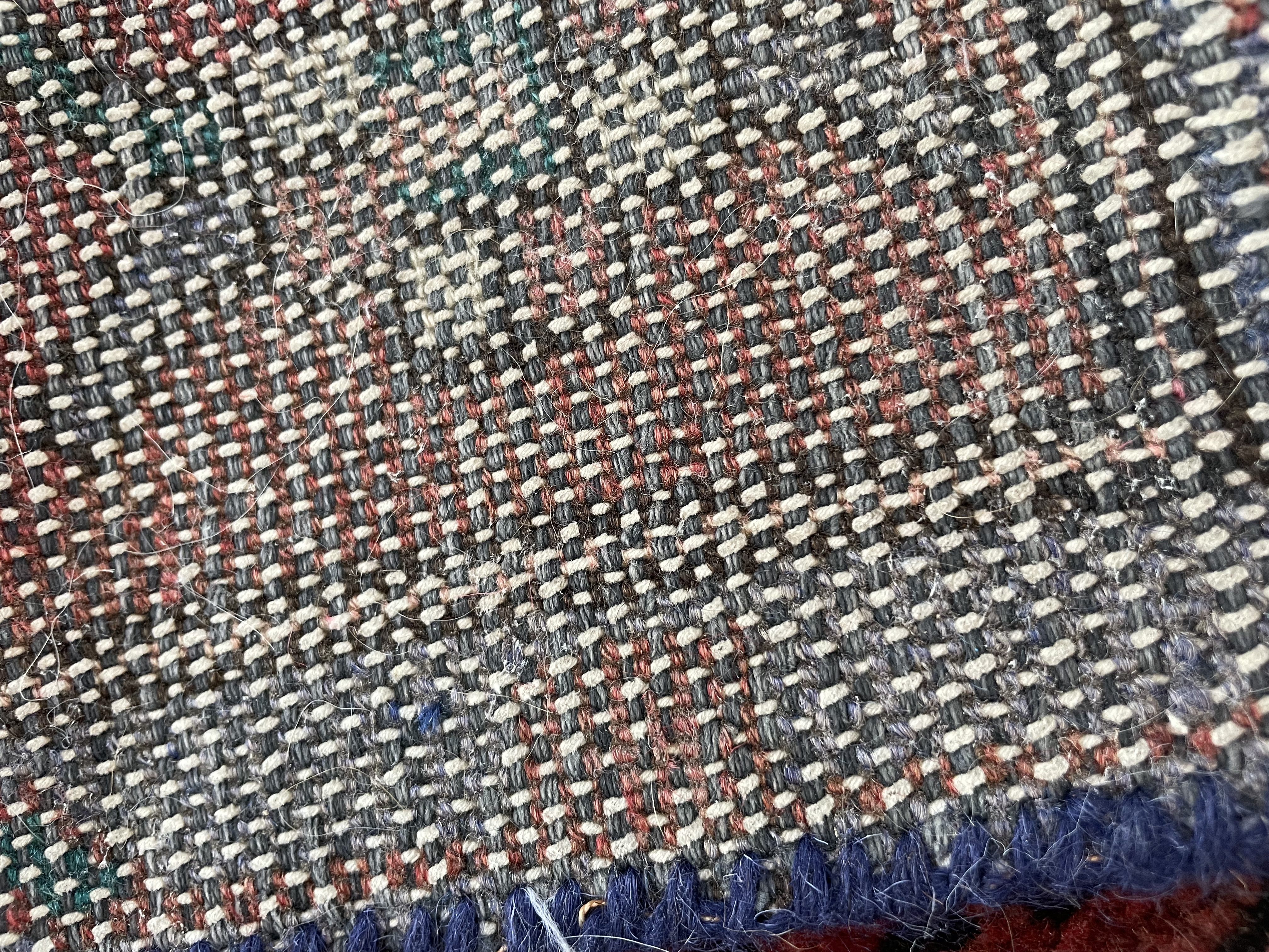 A traditional runner rug with a central medallion design, featuring geometric patterns and a rich palette of reds, purples, and blues.