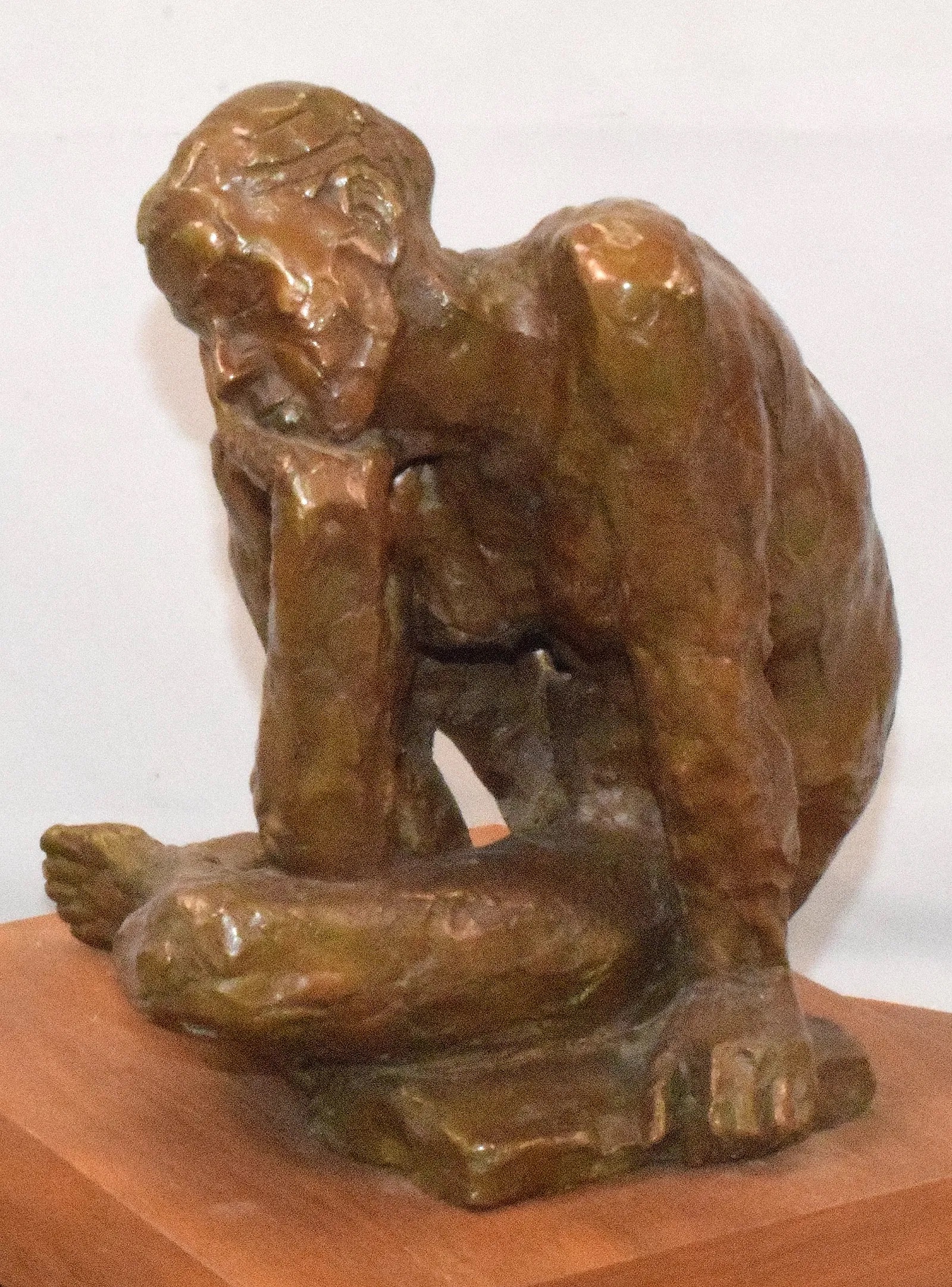 A bronze sculpture of a seated figure in deep contemplation.