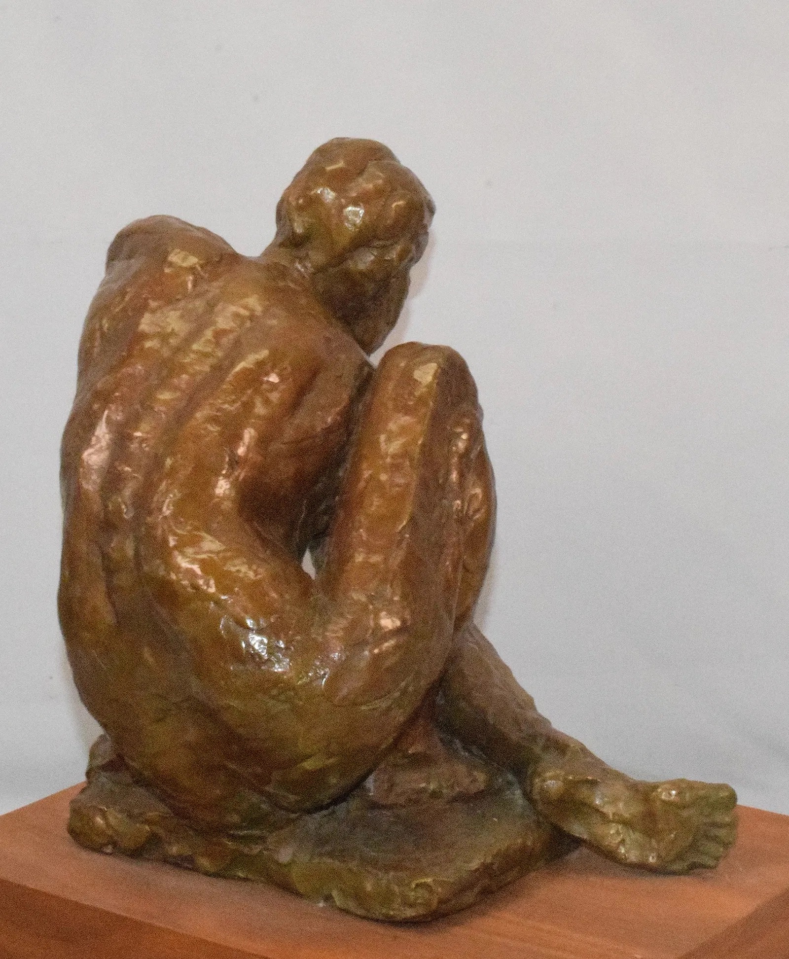 A bronze sculpture of a seated figure in deep contemplation.