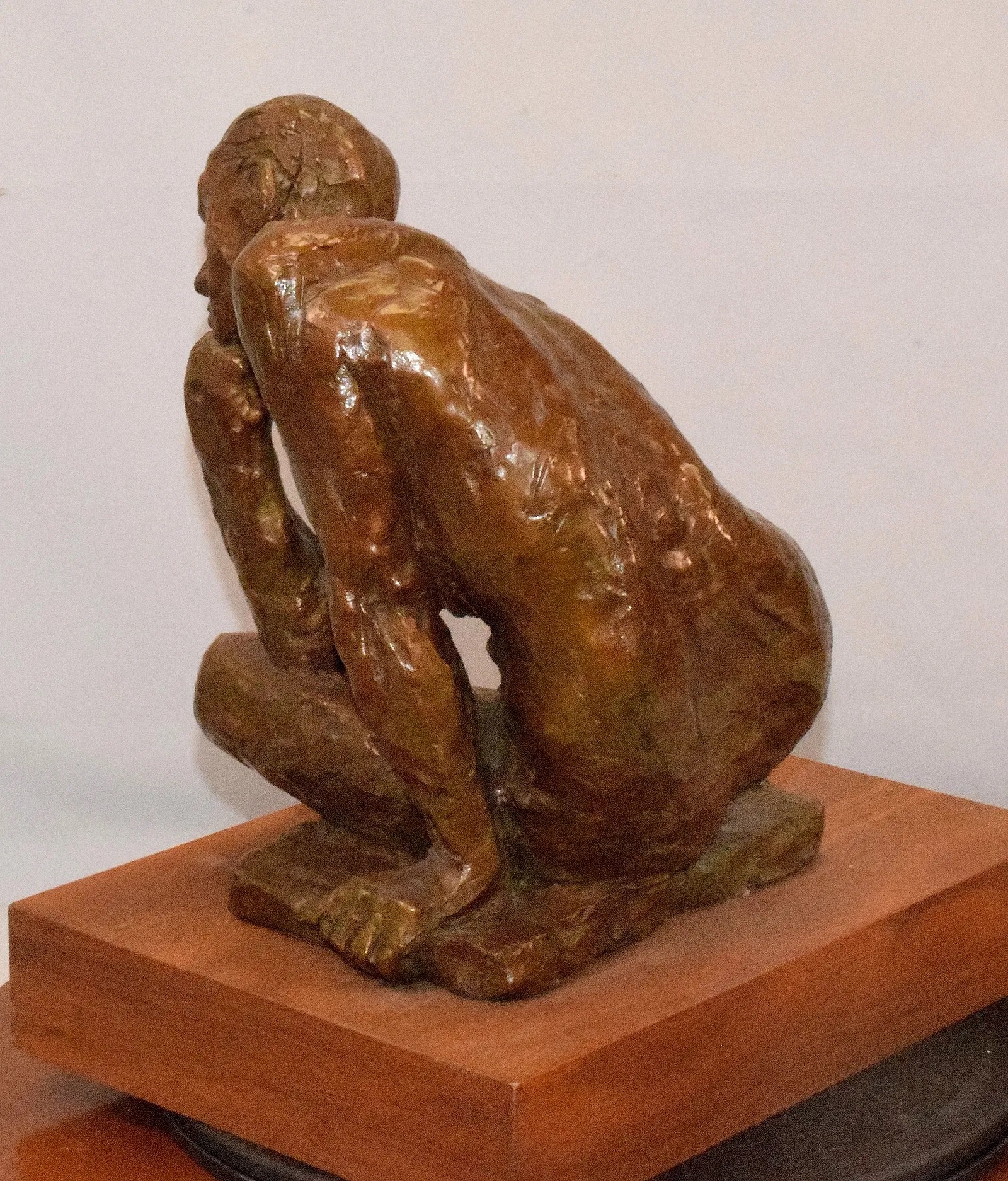 A bronze sculpture of a seated figure in deep contemplation.