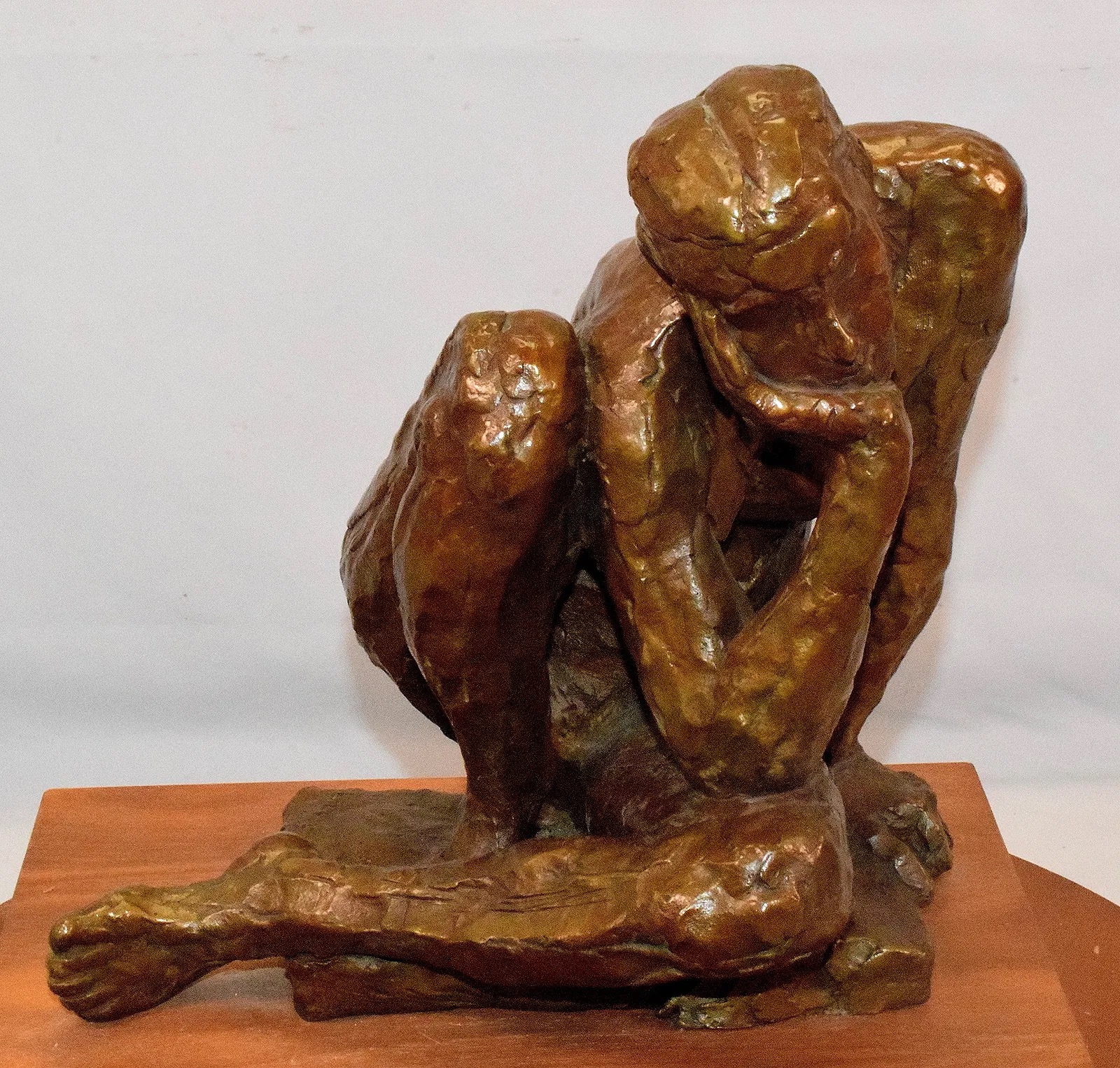 A bronze sculpture of a seated figure in deep contemplation.