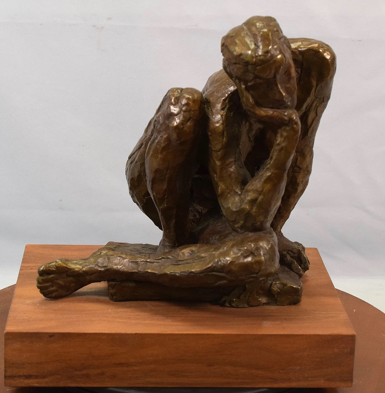 A bronze sculpture of a seated figure in deep contemplation.