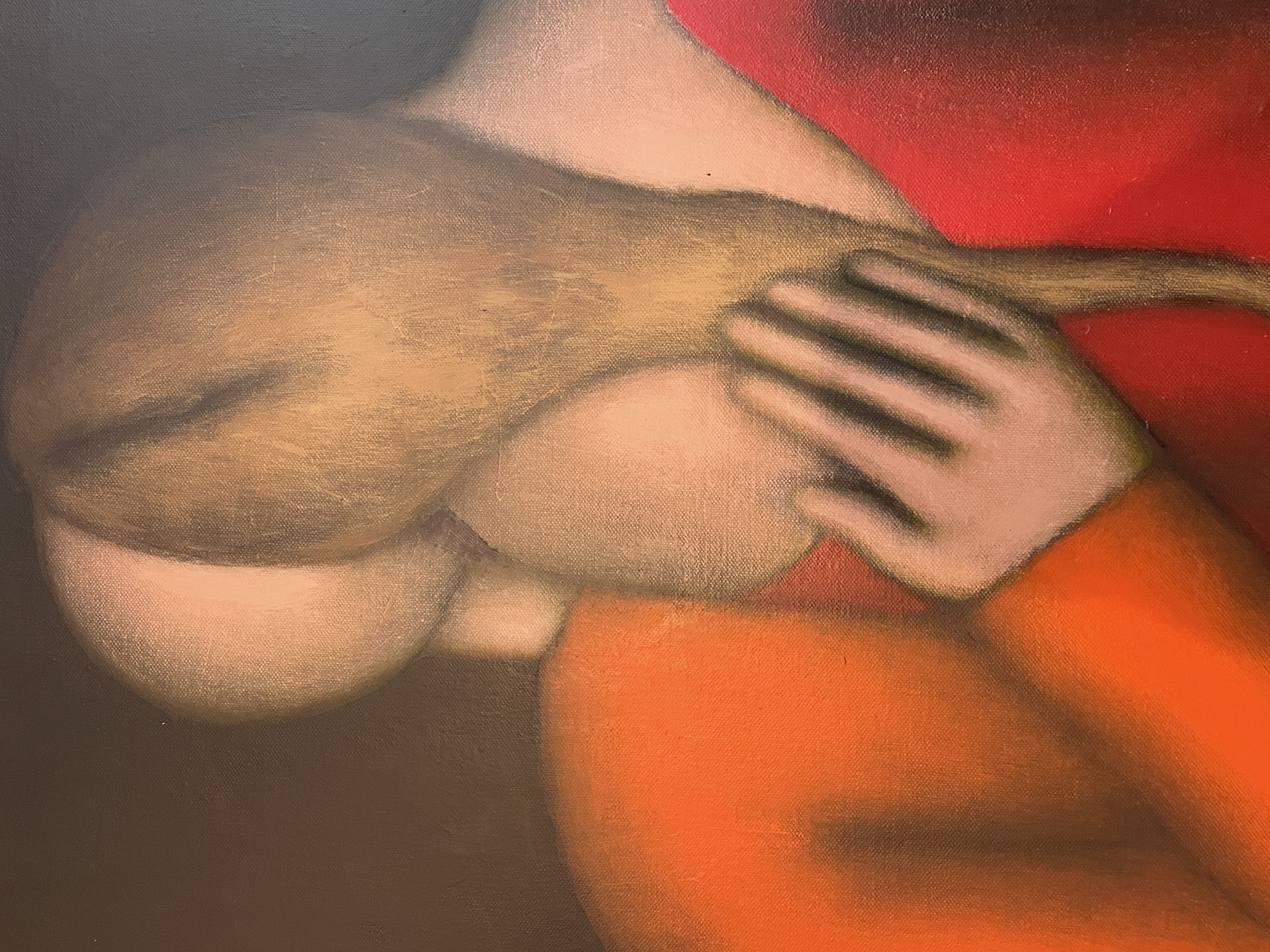 A man in a suit observes a painting of two figures embracing on red chairs.