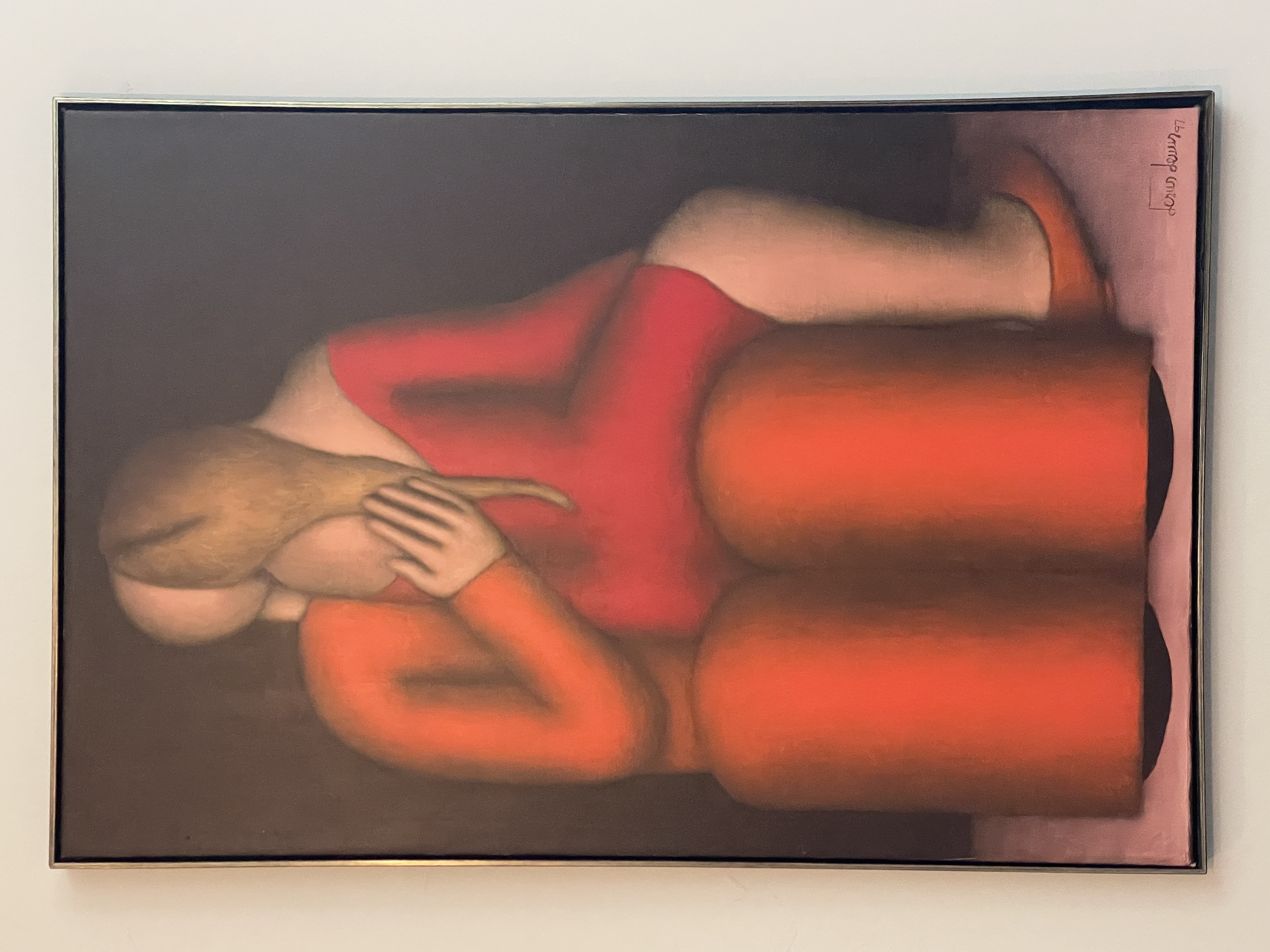 A man in a suit observes a painting of two figures embracing on red chairs.
