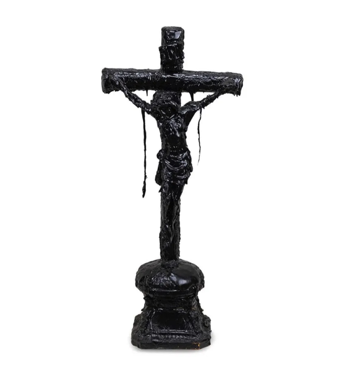 A dark, textured sculpture of a crucifixion scene displayed on a black marble pedestal.