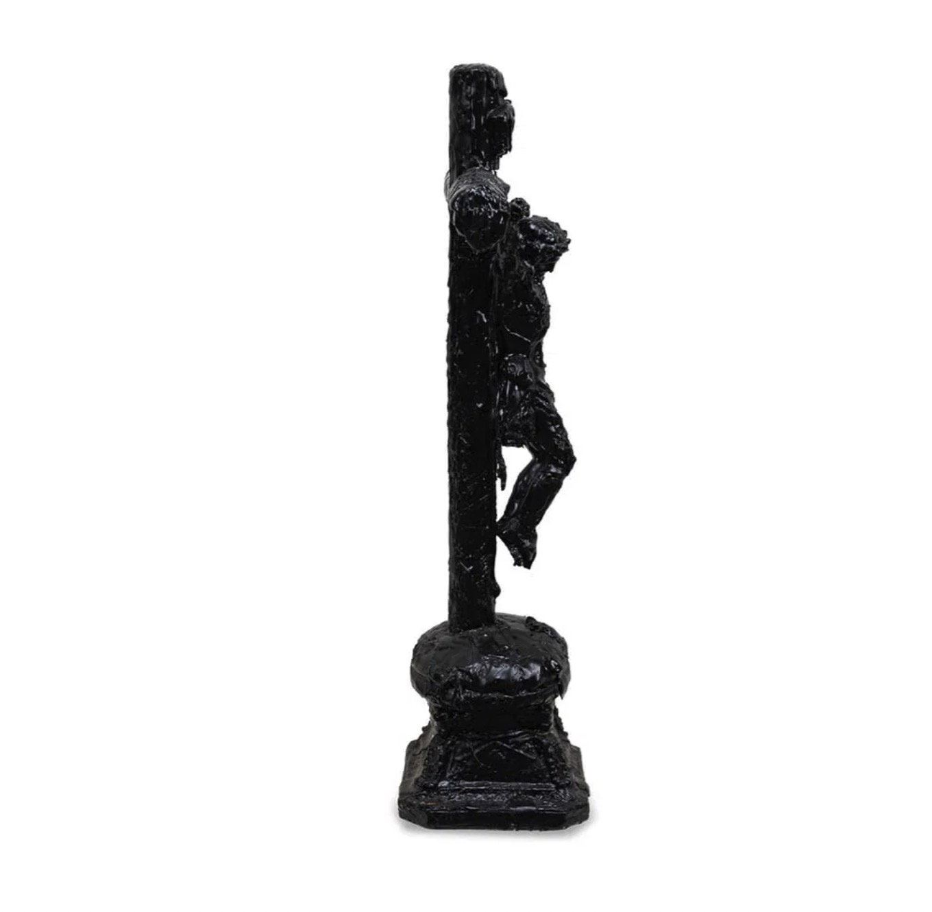 A dark, textured sculpture of a crucifixion scene displayed on a black marble pedestal.