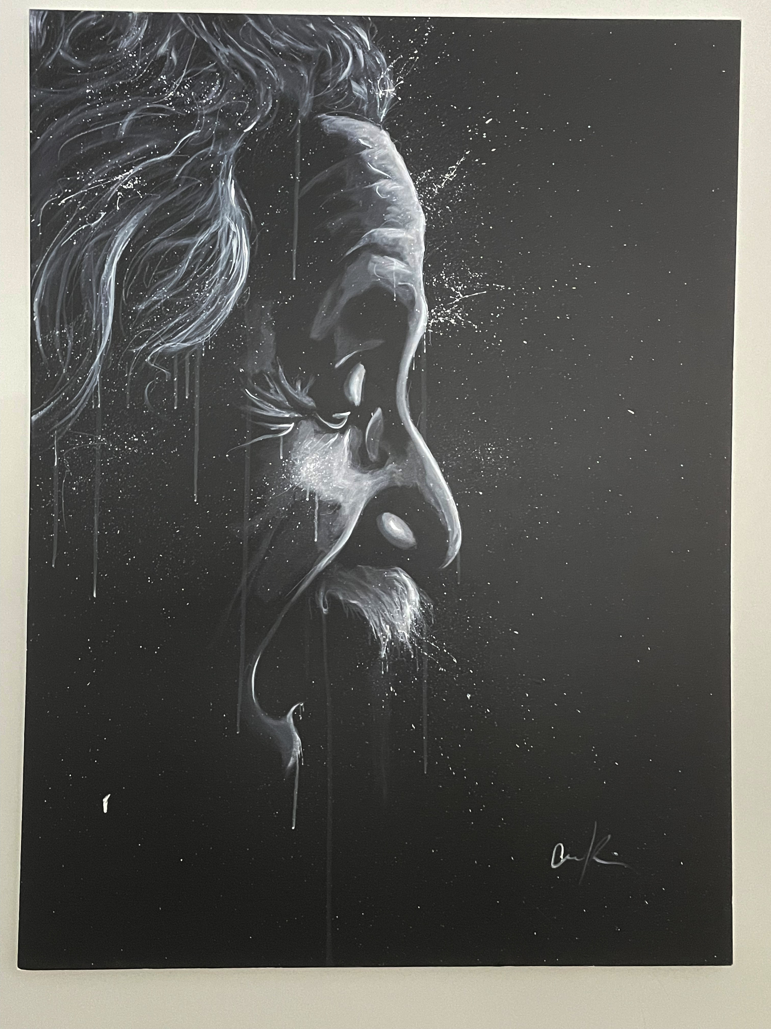 A contemplative figure stands before a dramatic black-and-white portrait in an art gallery.
