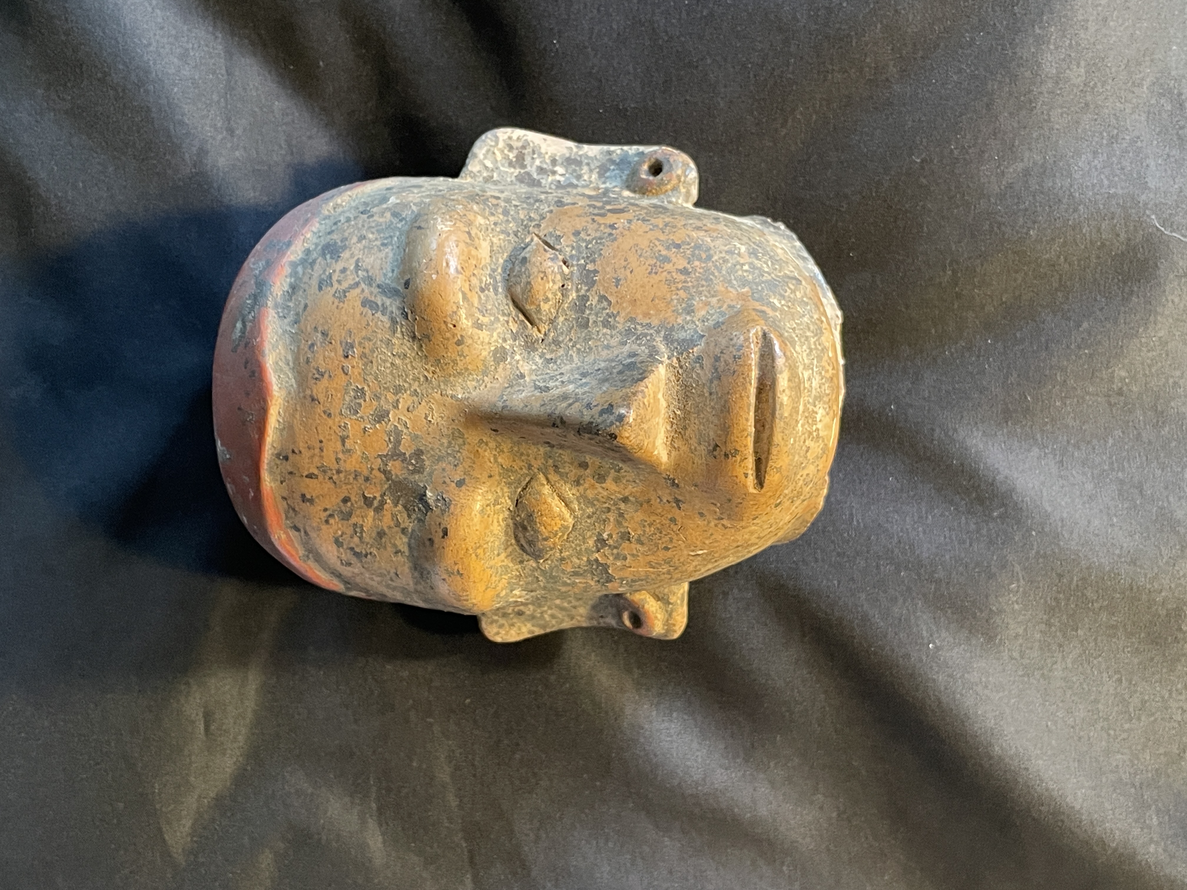 A ceramic head fragment displayed in a glass case within an art gallery.