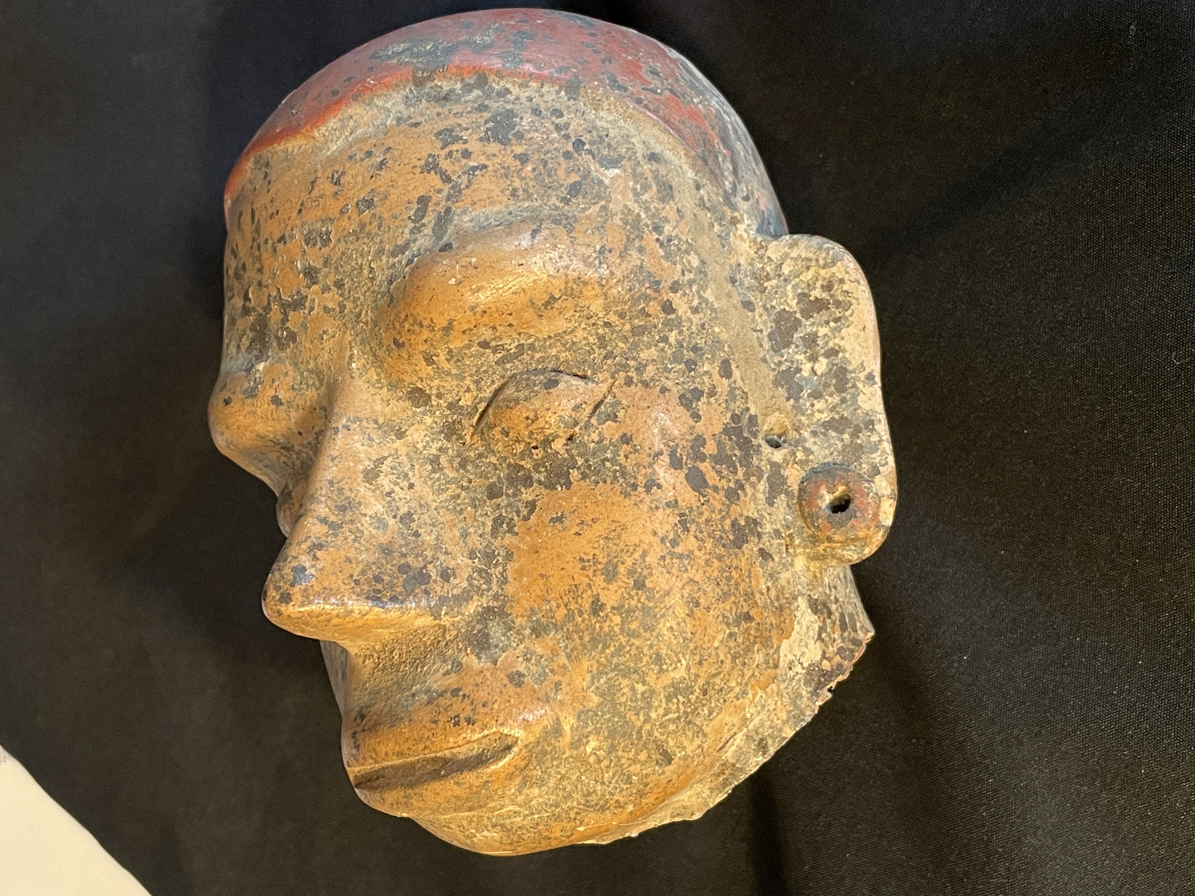 A ceramic head fragment displayed in a glass case within an art gallery.