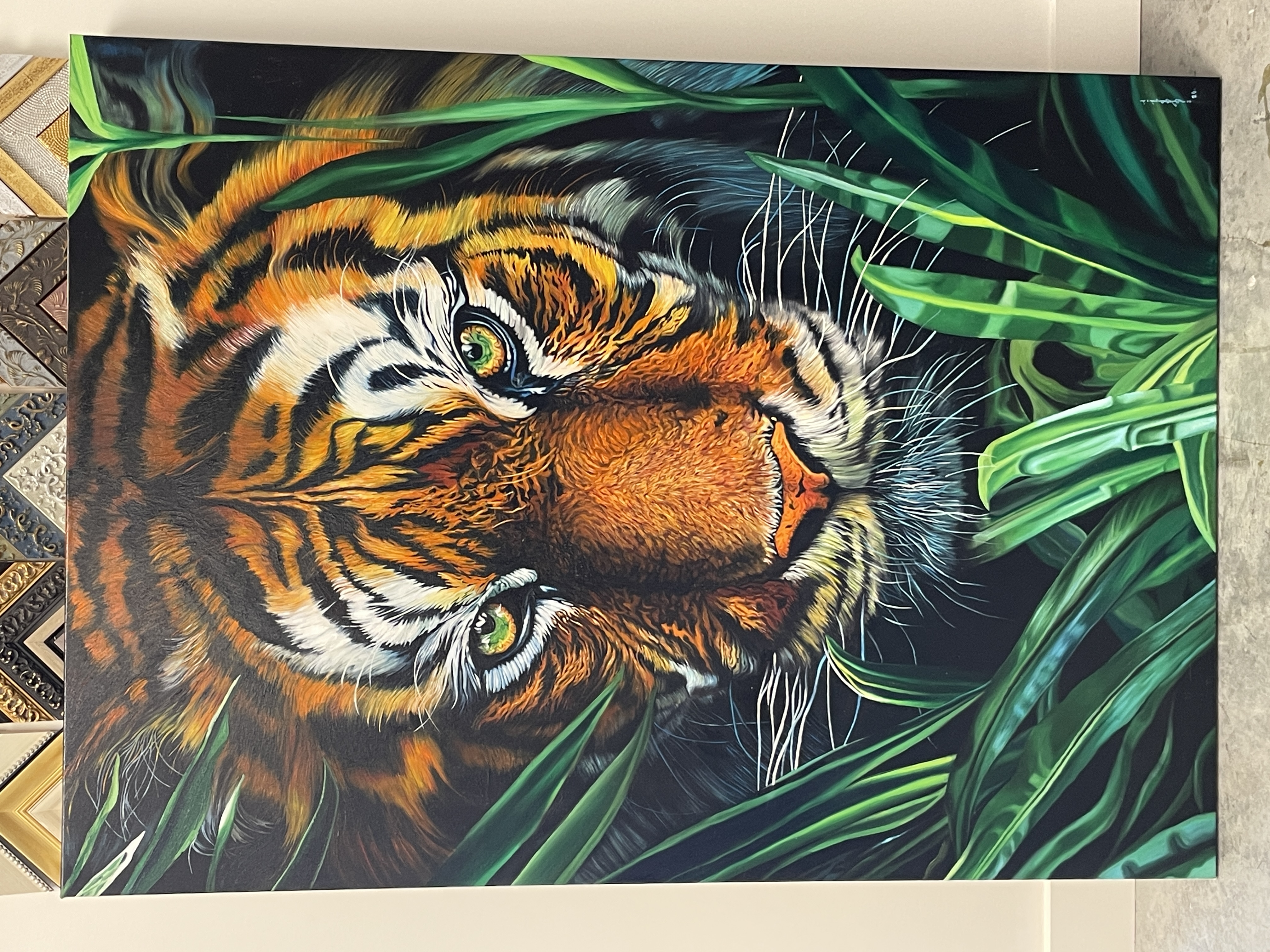 A person in a suit observes a large, hyper-realistic tiger painting amidst lush green foliage.