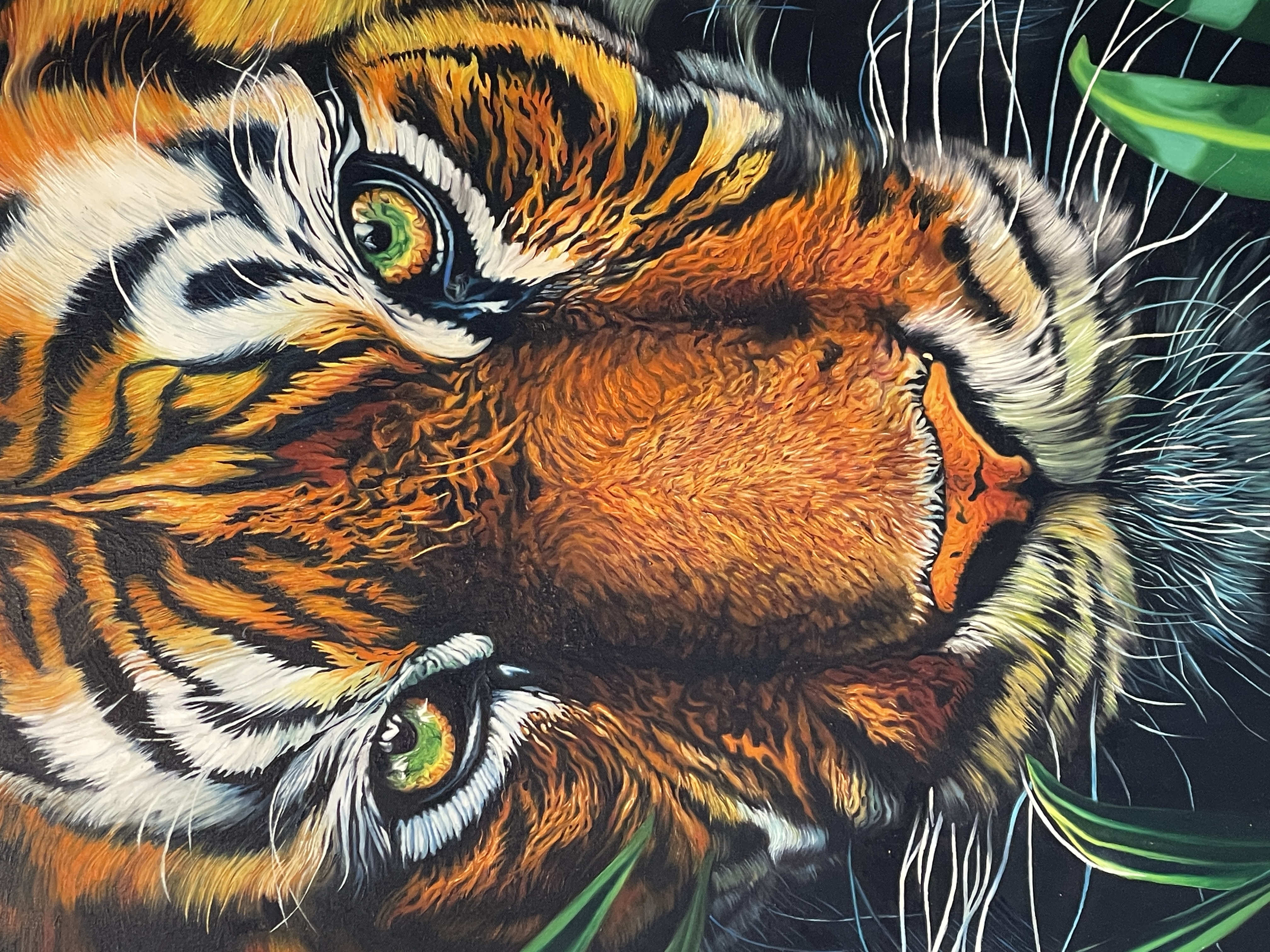A person in a suit observes a large, hyper-realistic tiger painting amidst lush green foliage.