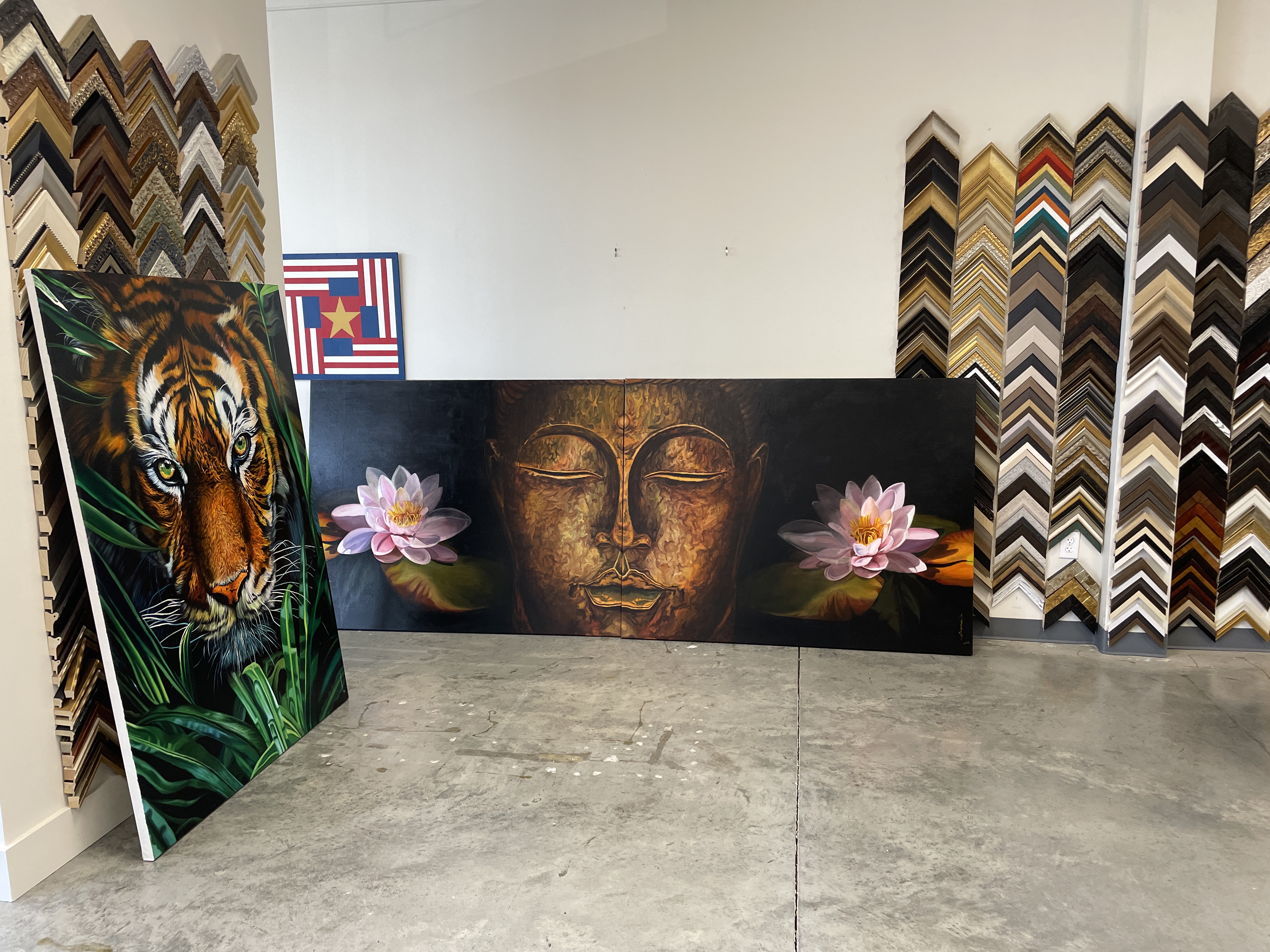 A person stands in a gallery, observing a large painting of a golden face flanked by pink lotus flowers.