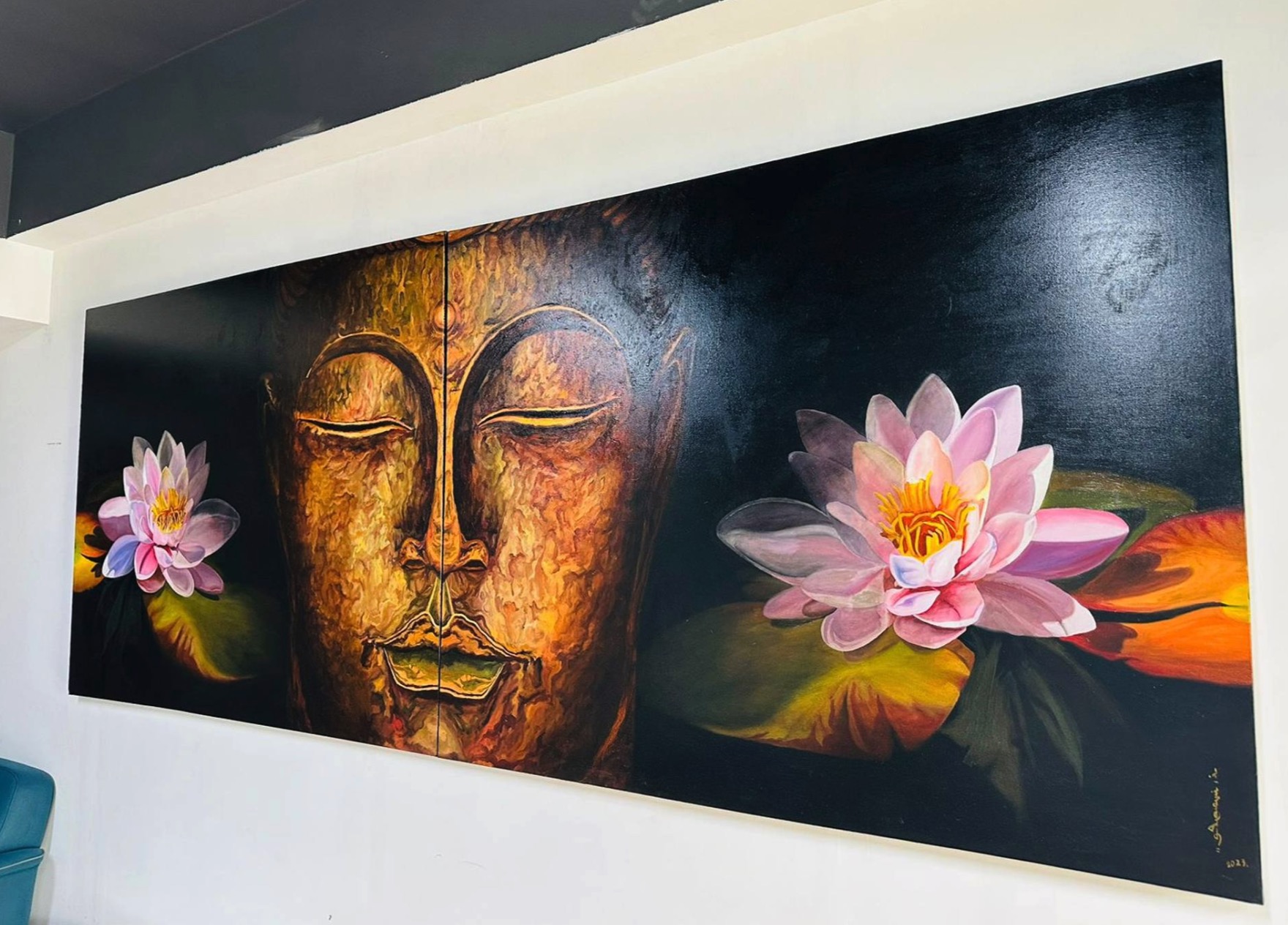 A person stands in a gallery, observing a large painting of a golden face flanked by pink lotus flowers.