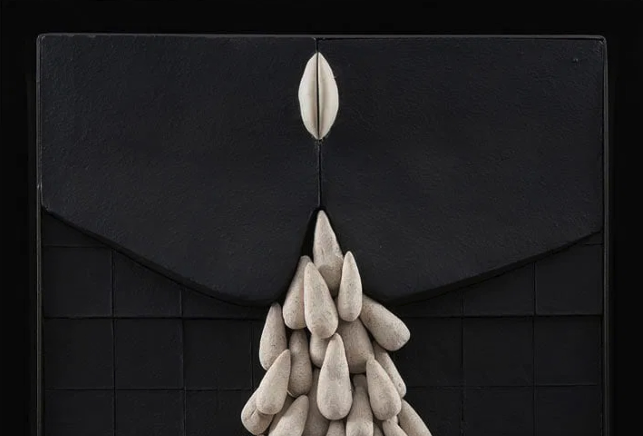 A sculptural composition featuring a cluster of teardrop shapes emerging from a dark, grid-like surface.