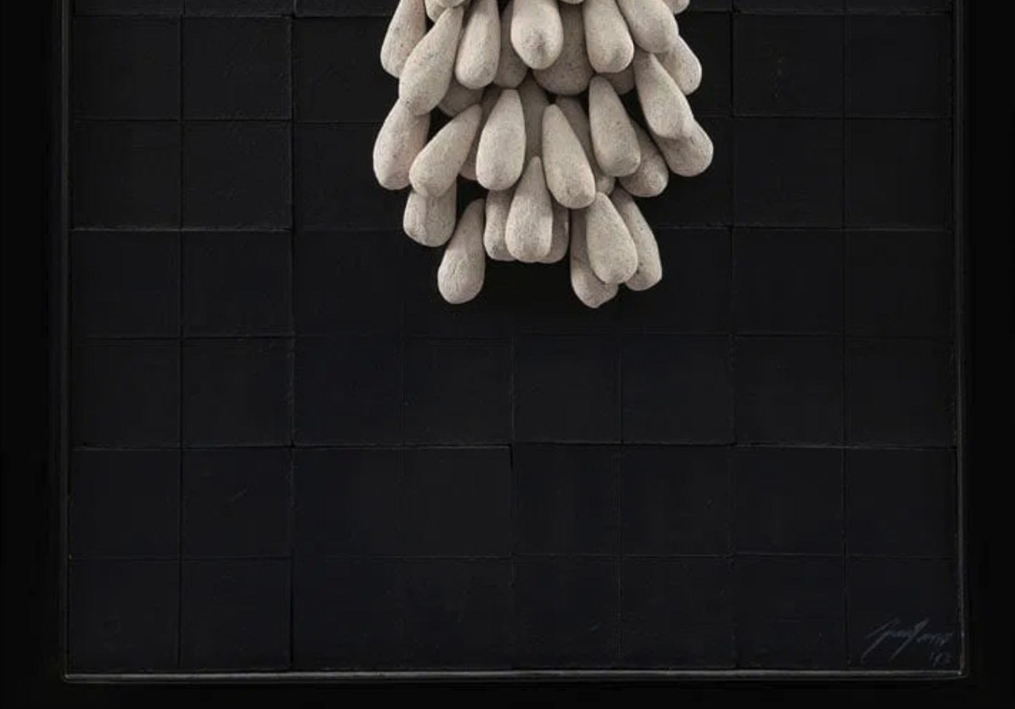 A sculptural composition featuring a cluster of teardrop shapes emerging from a dark, grid-like surface.