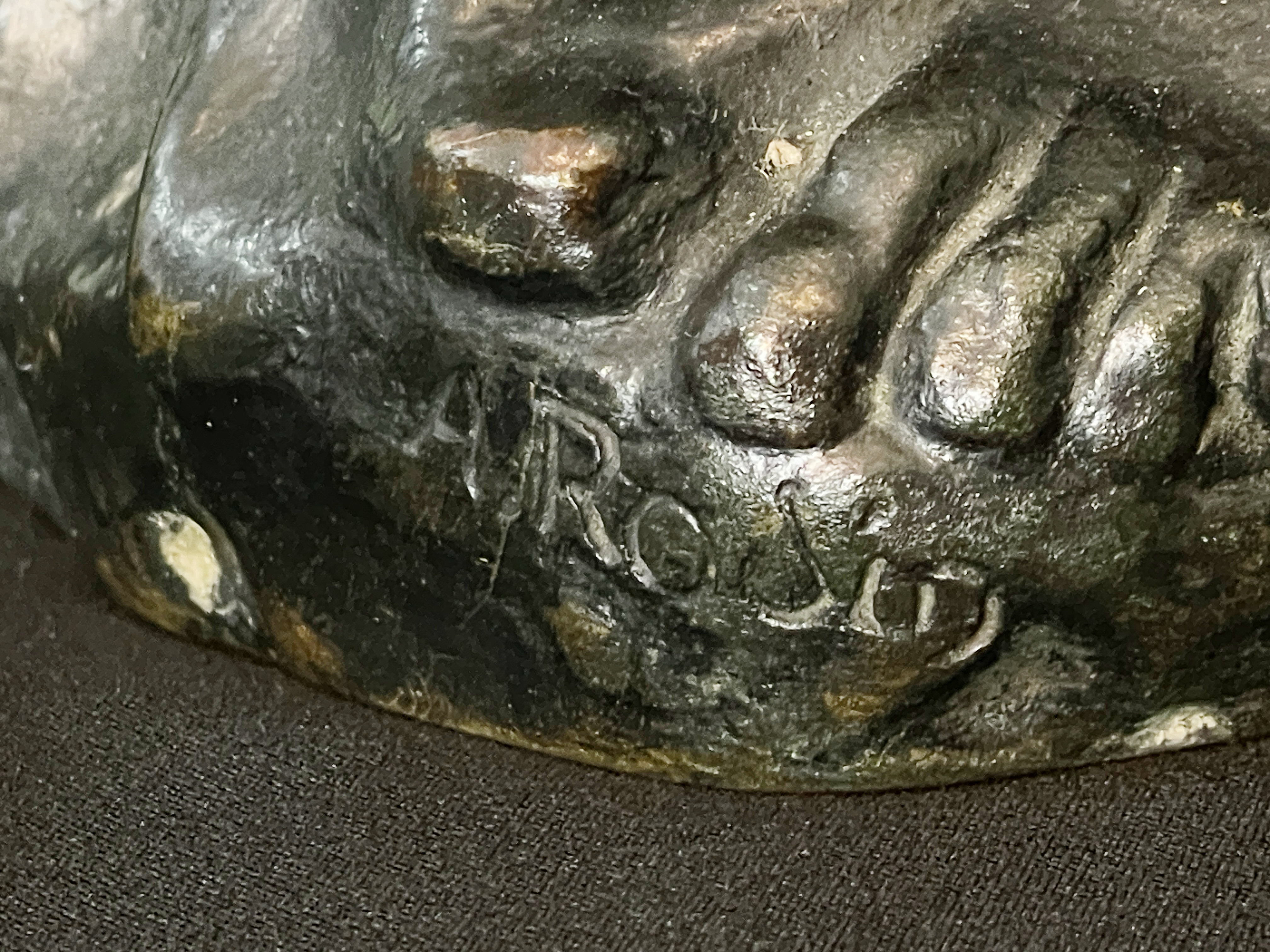 A museum display featuring a bronze statue, framed portraits, and an old book.