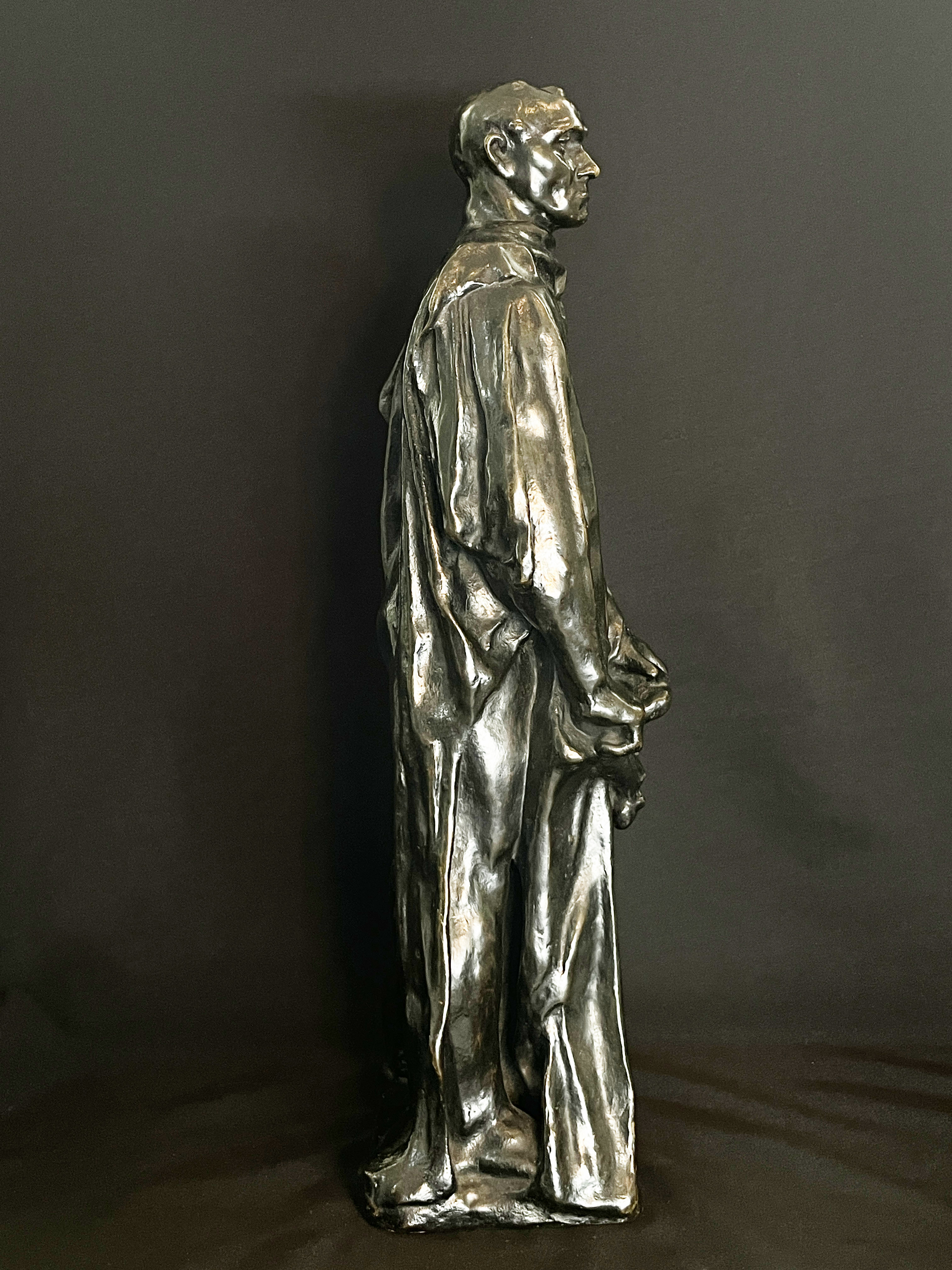 A museum display featuring a bronze statue, framed portraits, and an old book.