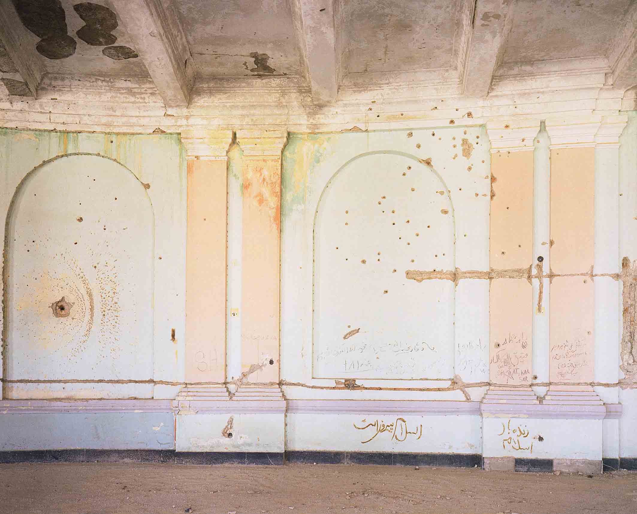 A room with peeling paint on the walls and ceiling. 