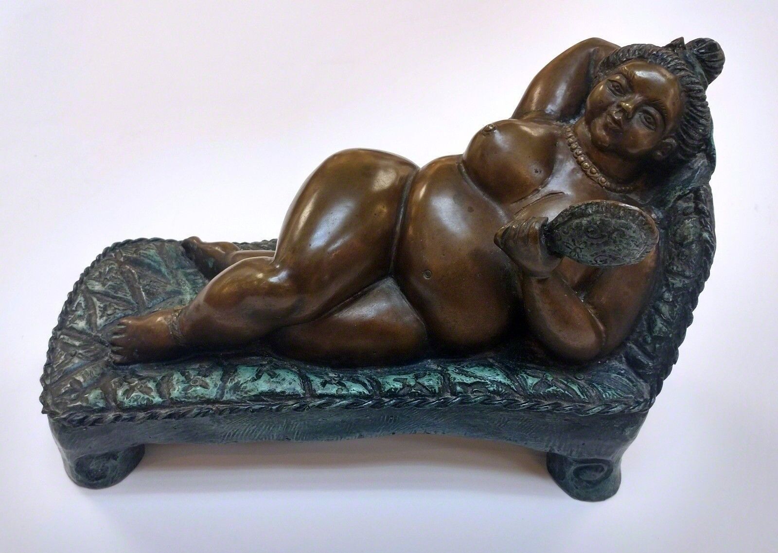 A bronze statue of a woman laying on a couch.