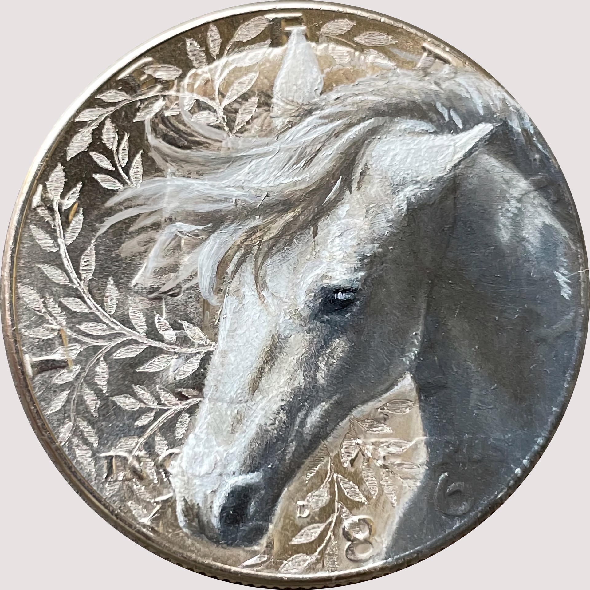 A silver coin with a white horse head on it.
