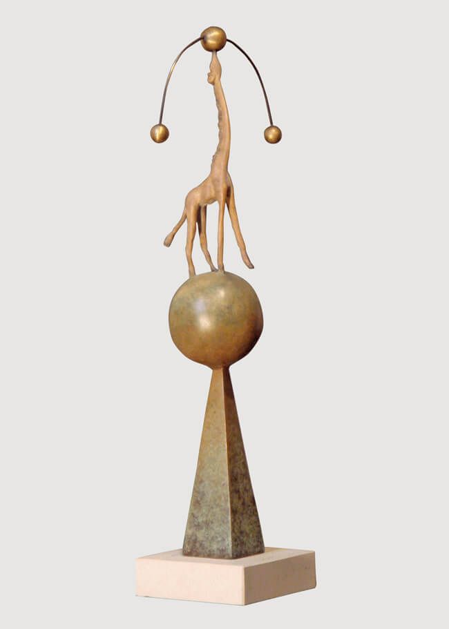 A whimsical sculpture of a giraffe balancing on a sphere atop a pyramid base.