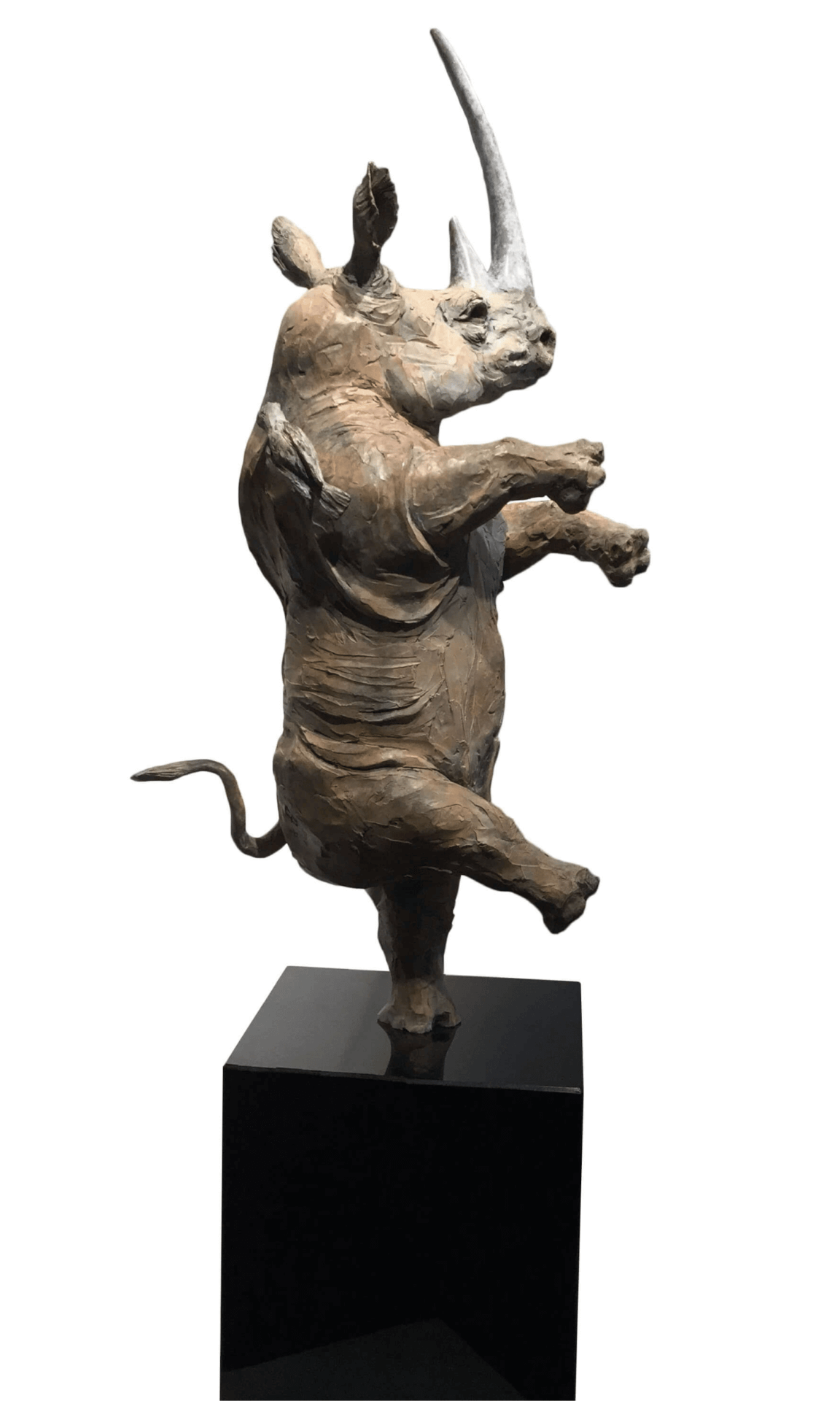 A bronze sculpture of a rhinoceros standing on one leg in a dynamic pose.