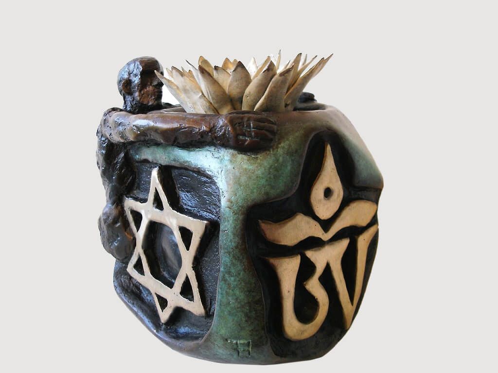 A sculpted ceramic vessel featuring a seated figure, a Star of David, and an abstract symbol with a spiky top.