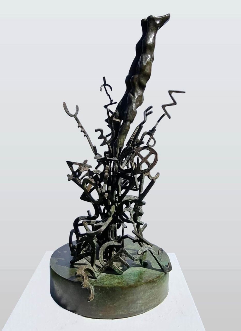 A bronze sculpture featuring a tangled mass of abstract metal forms erupting from a circular base.
