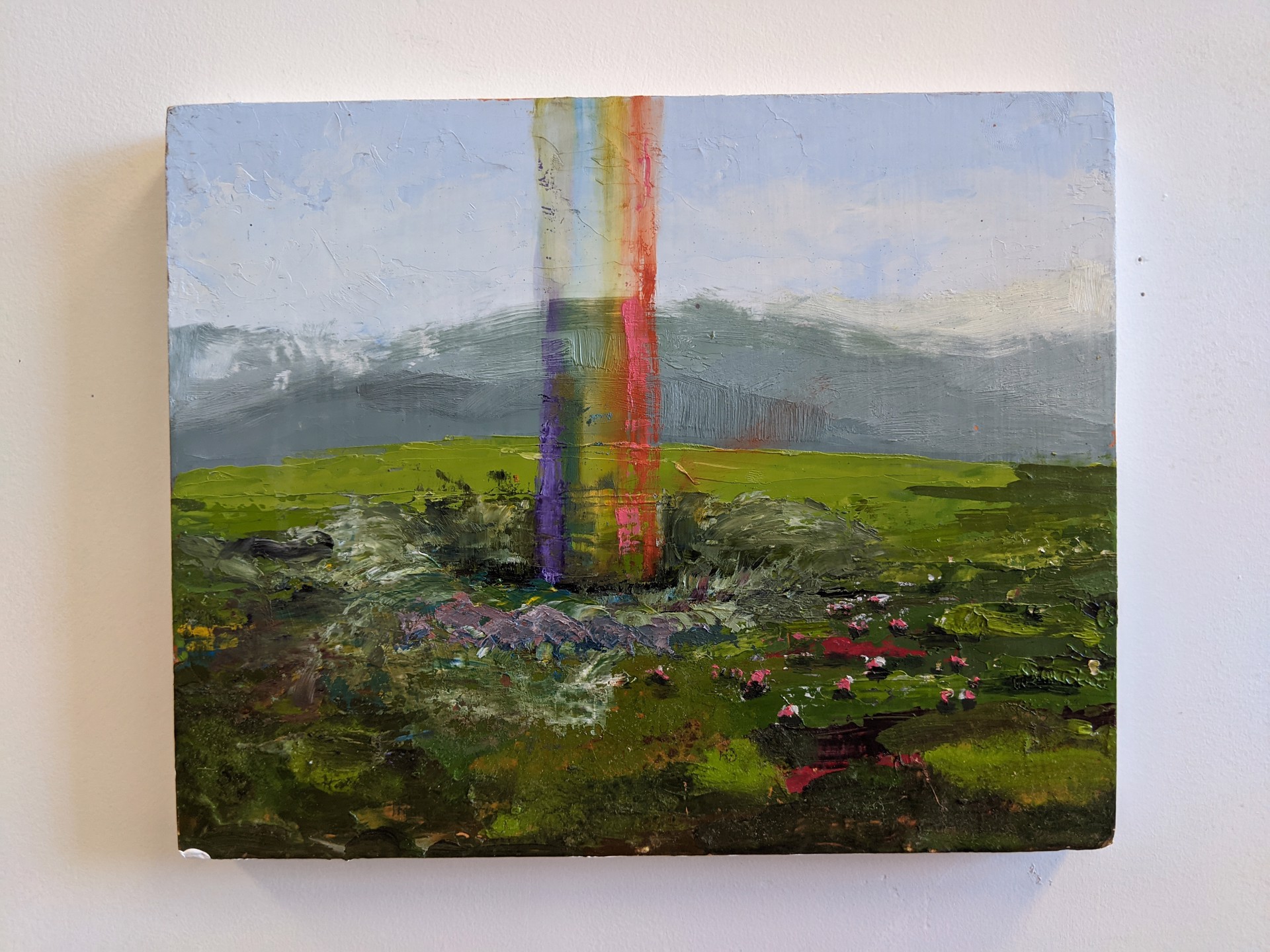 A painting of a rainbow in the middle of a field.