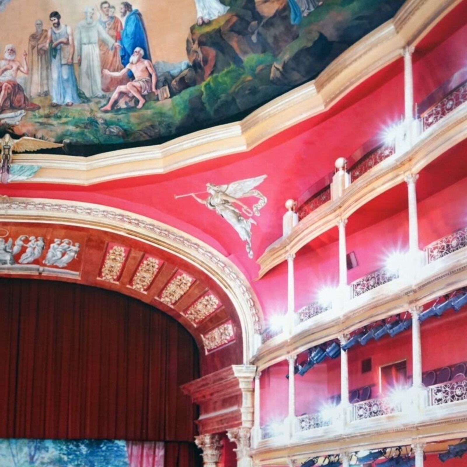 A picture of an empty theater with a painting on the ceiling.