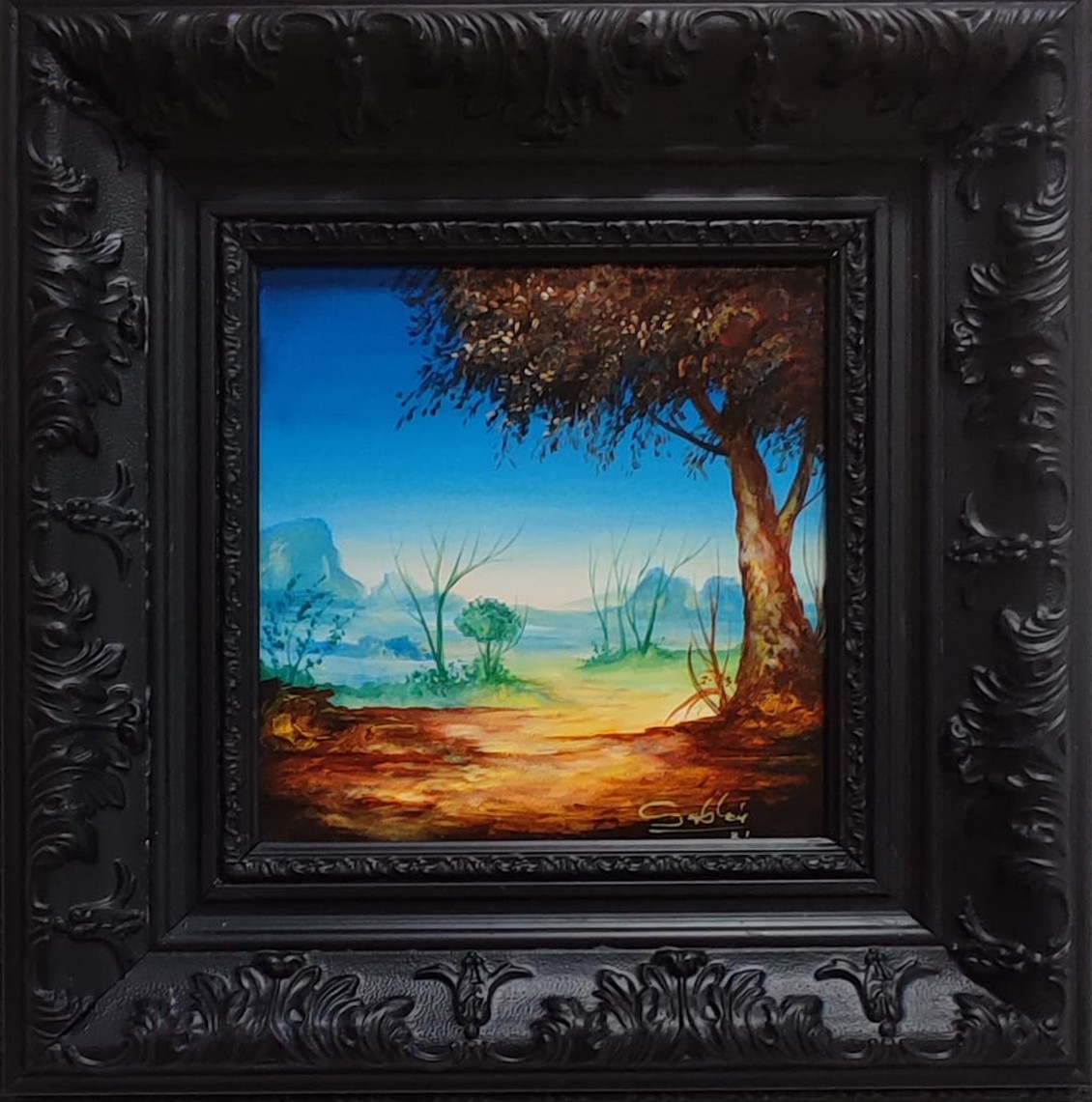 A painting of a landscape in a black frame.