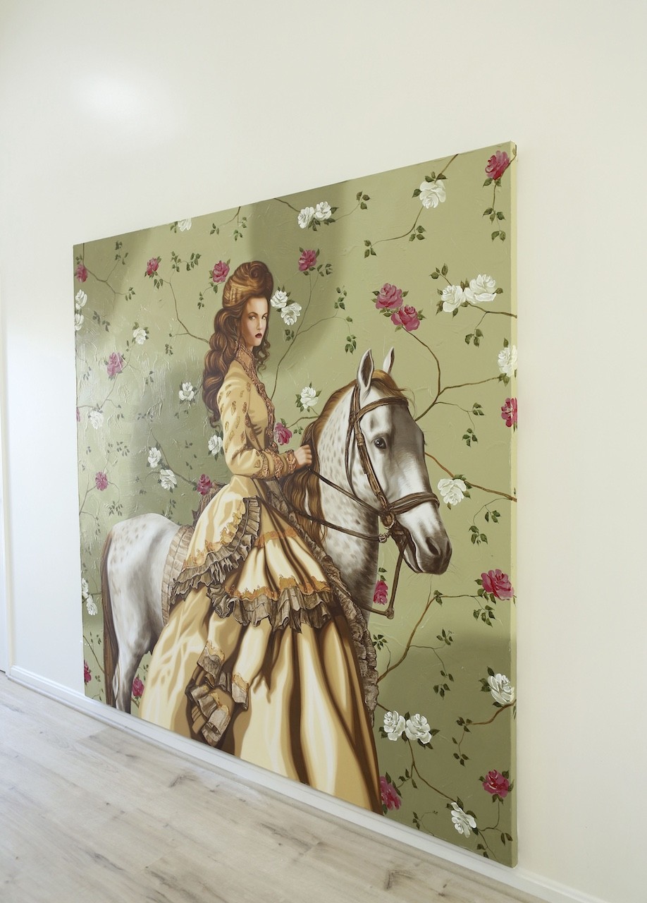 A woman riding a white horse in front of a floral wallpaper.