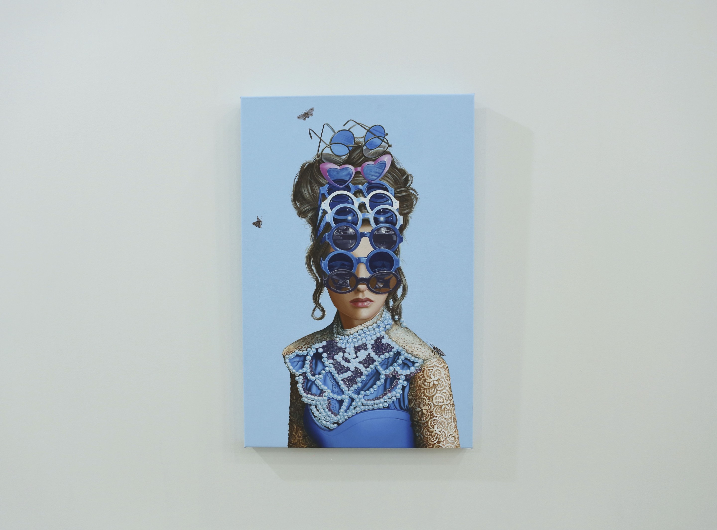 A painting of a woman wearing sunglasses on a wall.