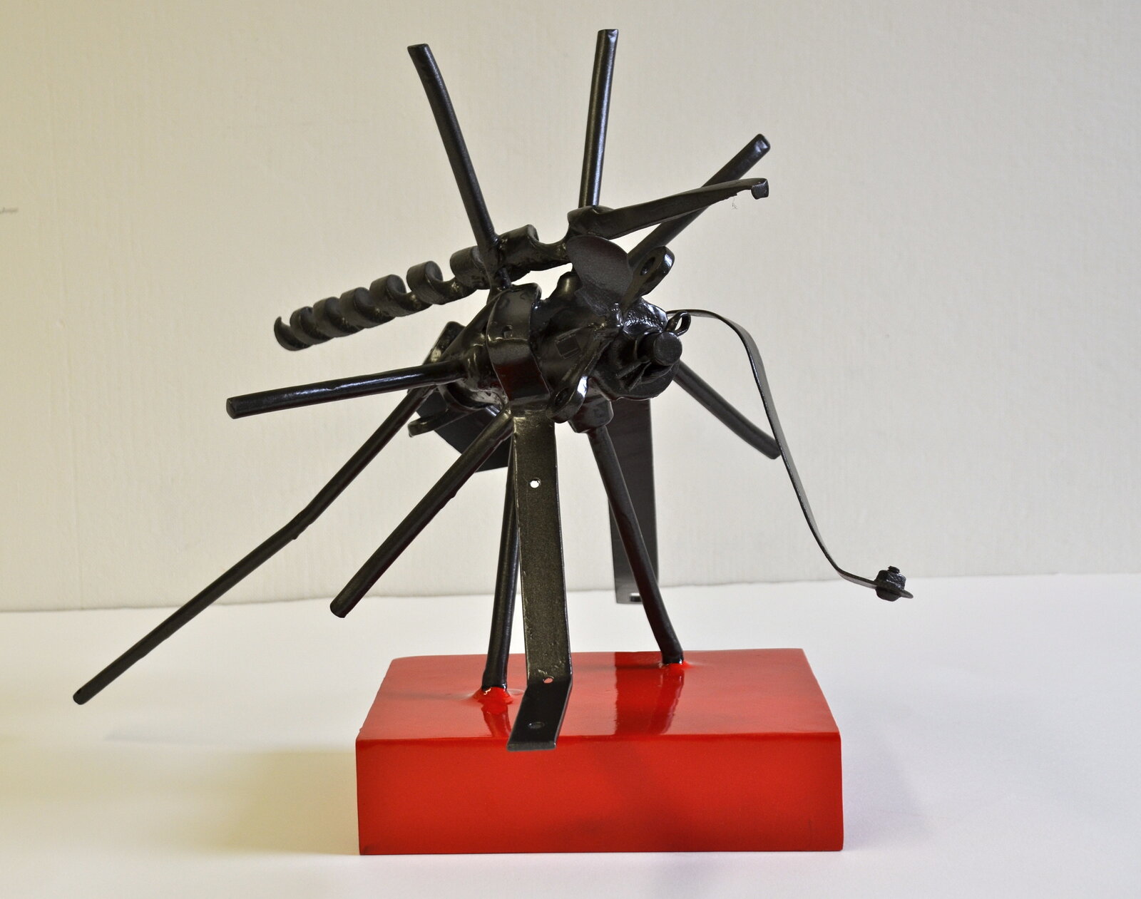 A metal sculpture of a spider on a red base.