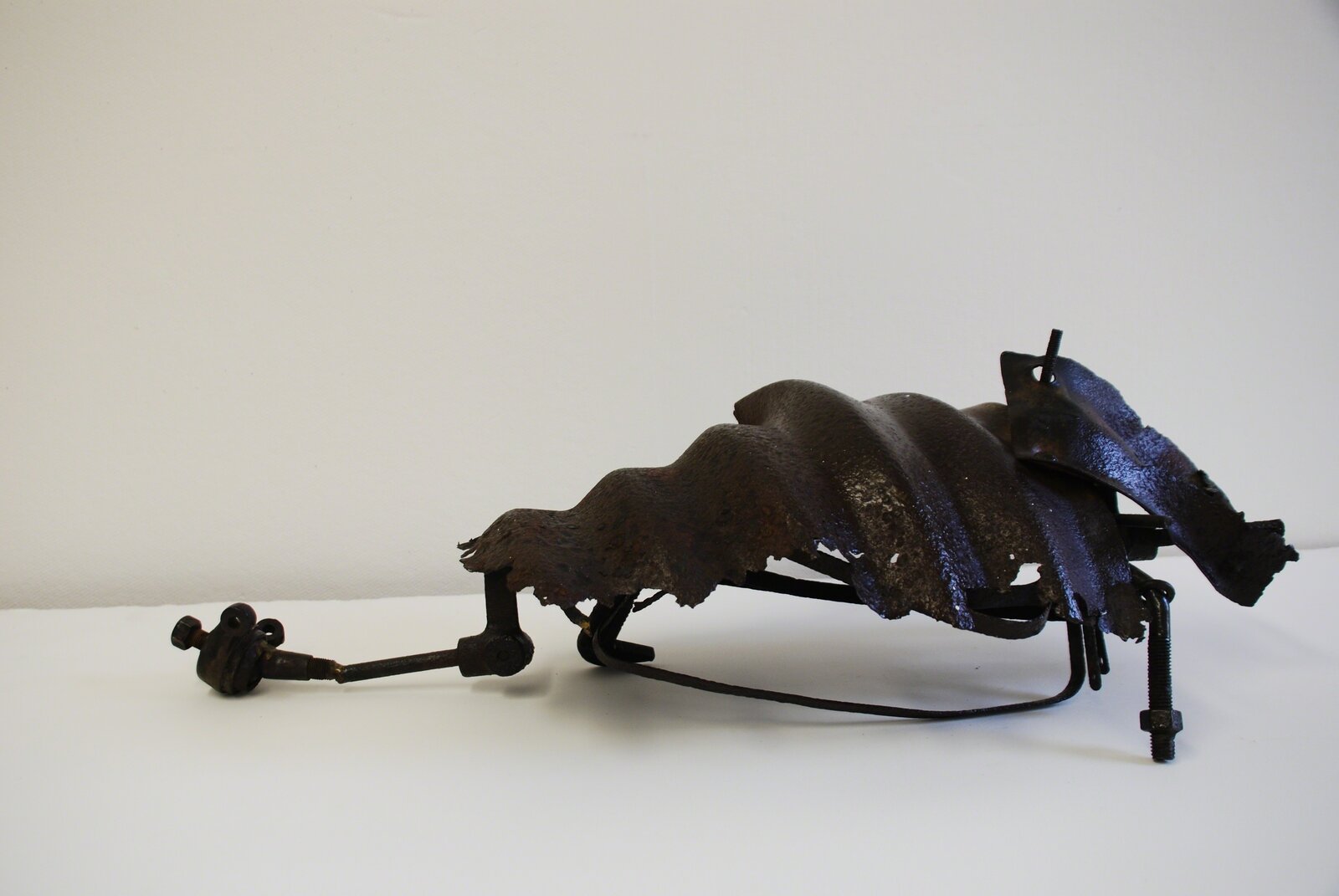 A metal sculpture of a horse on a white surface.