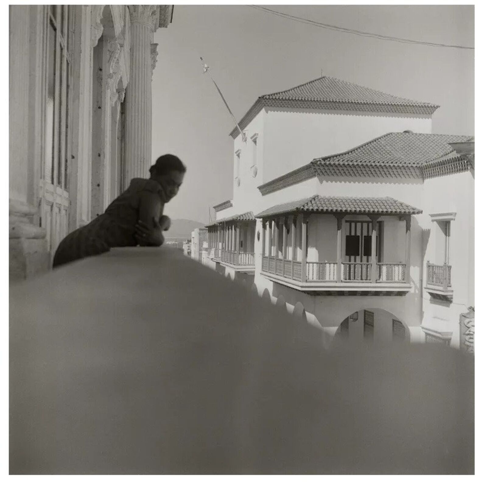 A black and white photo of a woman sitting on a ledge.