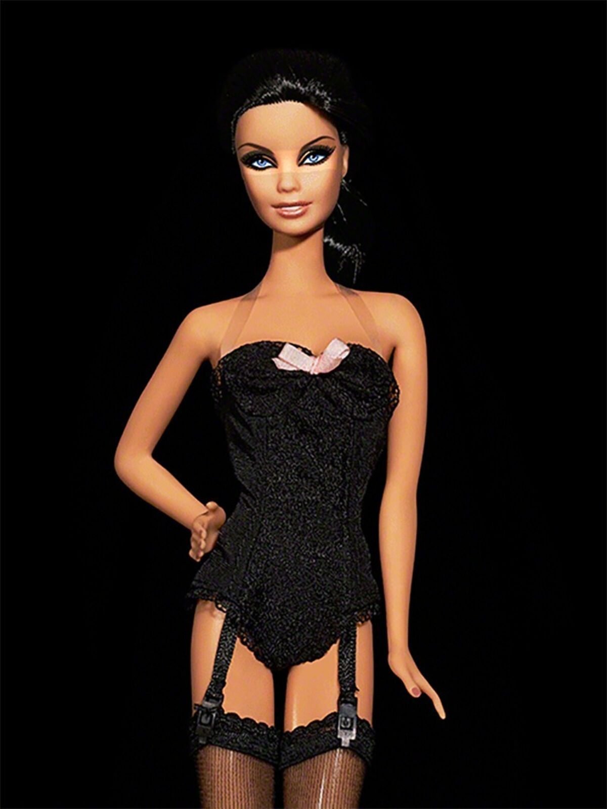 A barbie doll wearing a black corset and stockings.