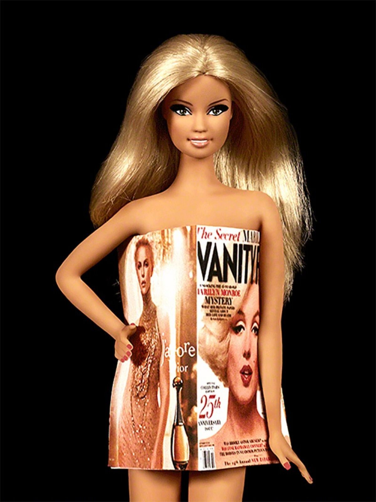 A barbie doll with blonde hair holding a magazine.