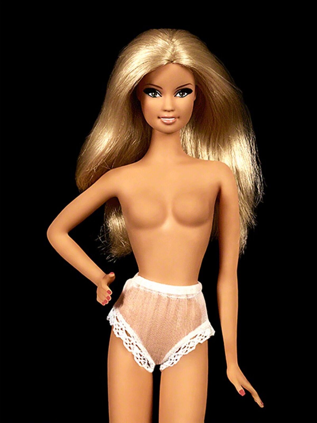 A barbie doll with blonde hair holding a magazine.