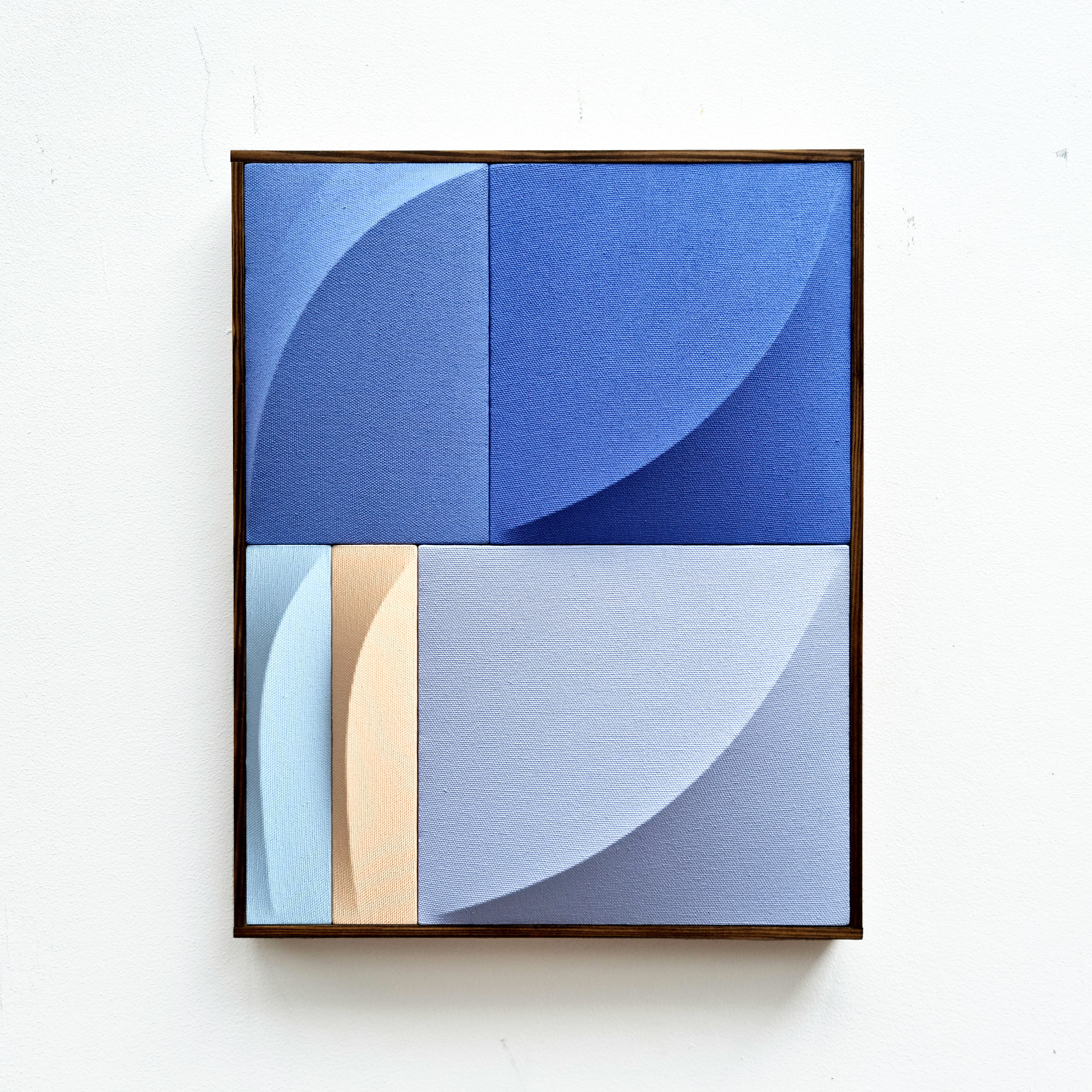 A blue and beige painting hanging on a white wall.